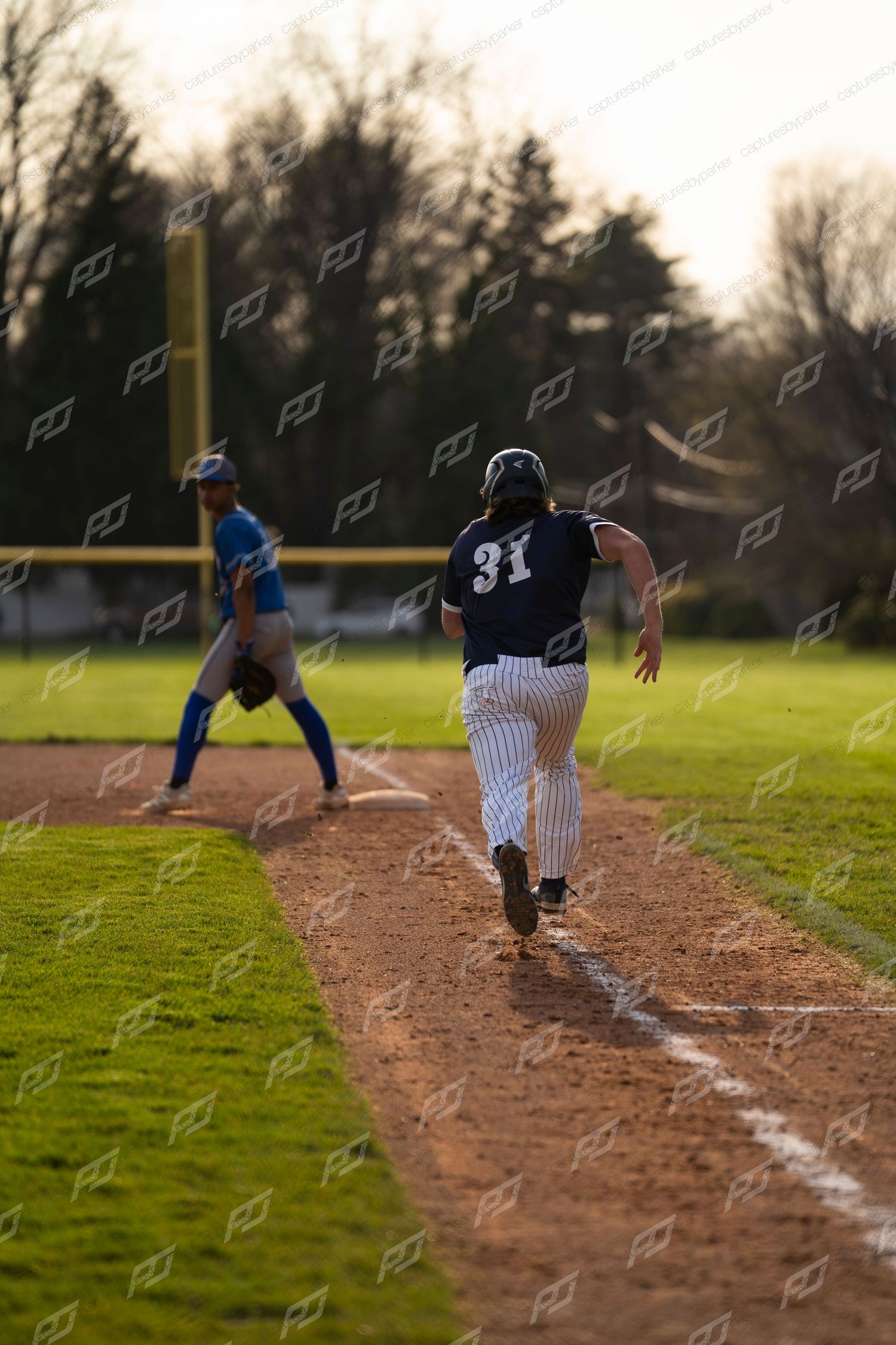 Baseball player #31 in dark pinstripe uniform sprints along the base path toward third base.