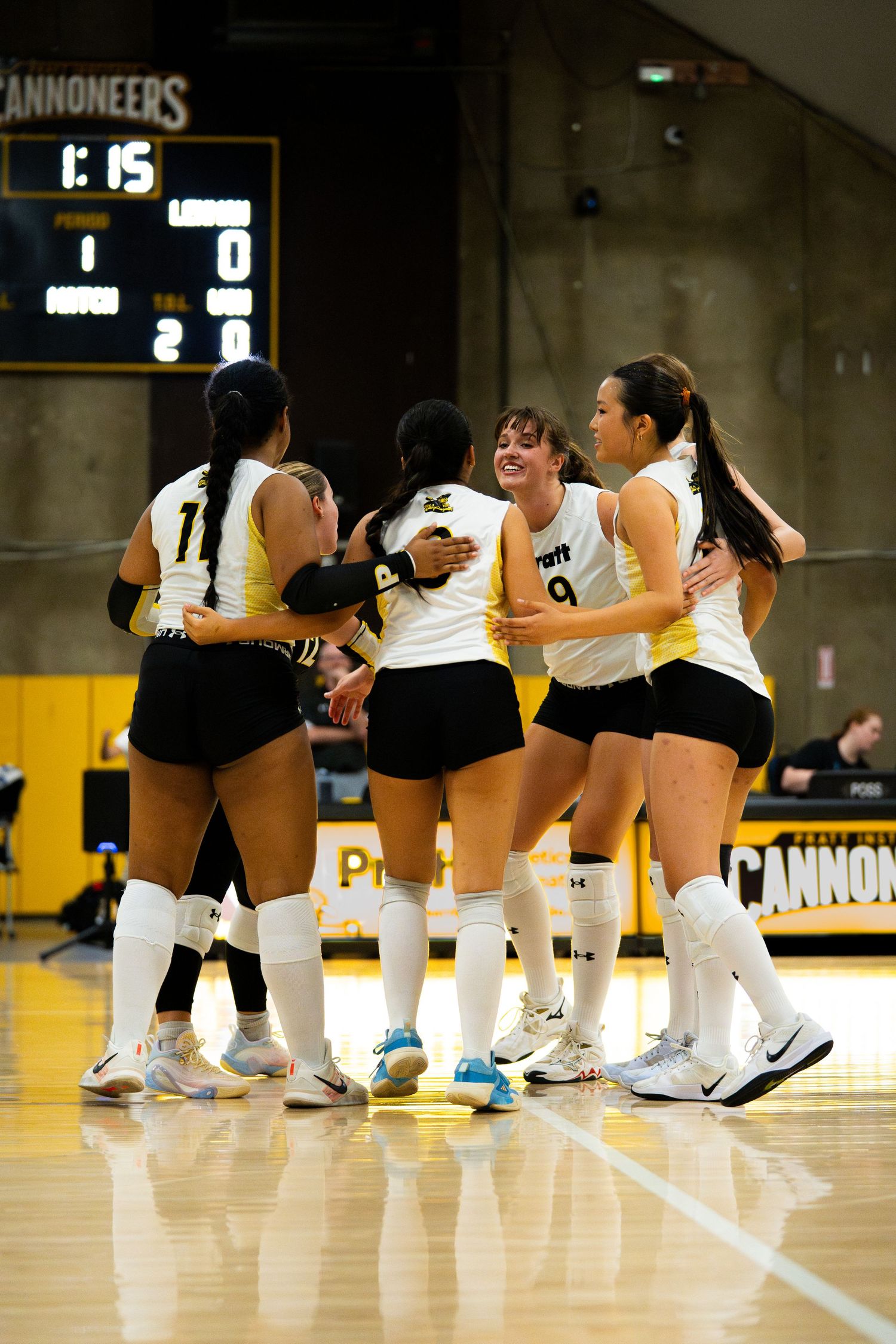 PFW Cannoneers volleyball team huddles together in celebration during a match at Purdue Fort Wayne.