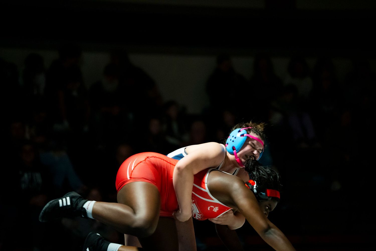 Two wrestlers in red uniforms grapple during an intense wrestling match.