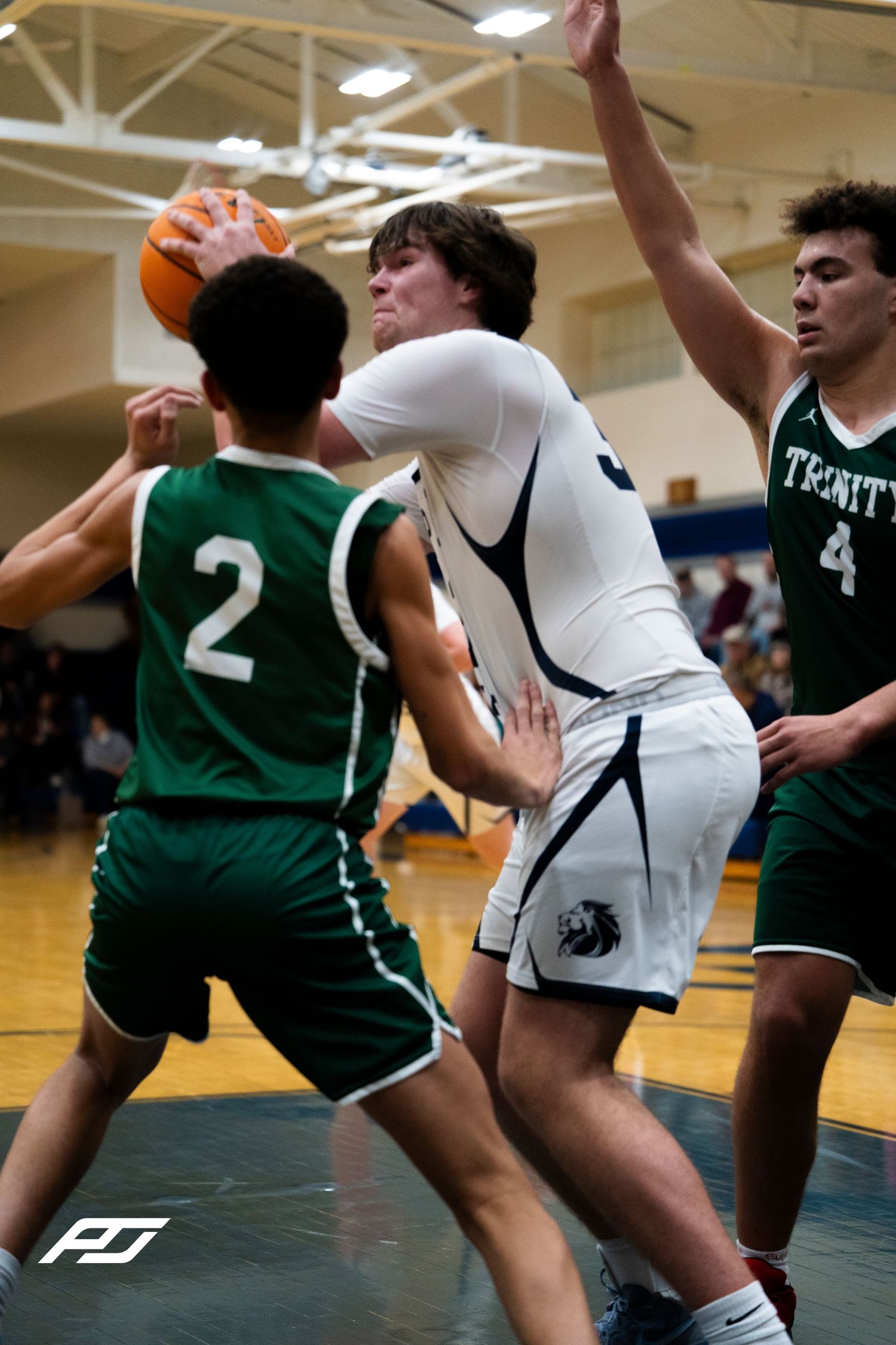 Camp Hill Lions player fights through Trinity #2 and #4 defenders during high school basketball game.