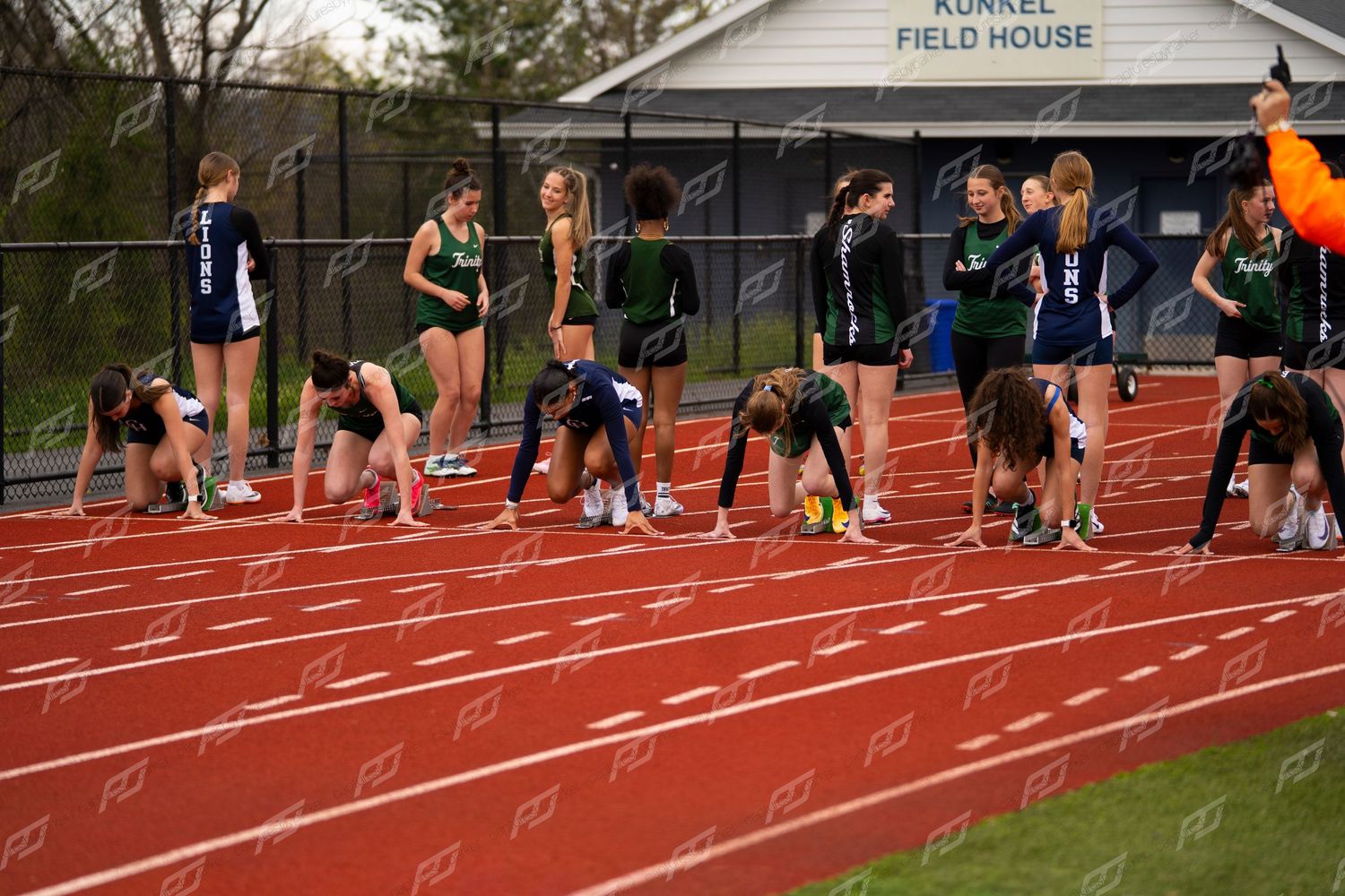 Runners set up at starting blocks on red track at Kunkel Field House track and field event.