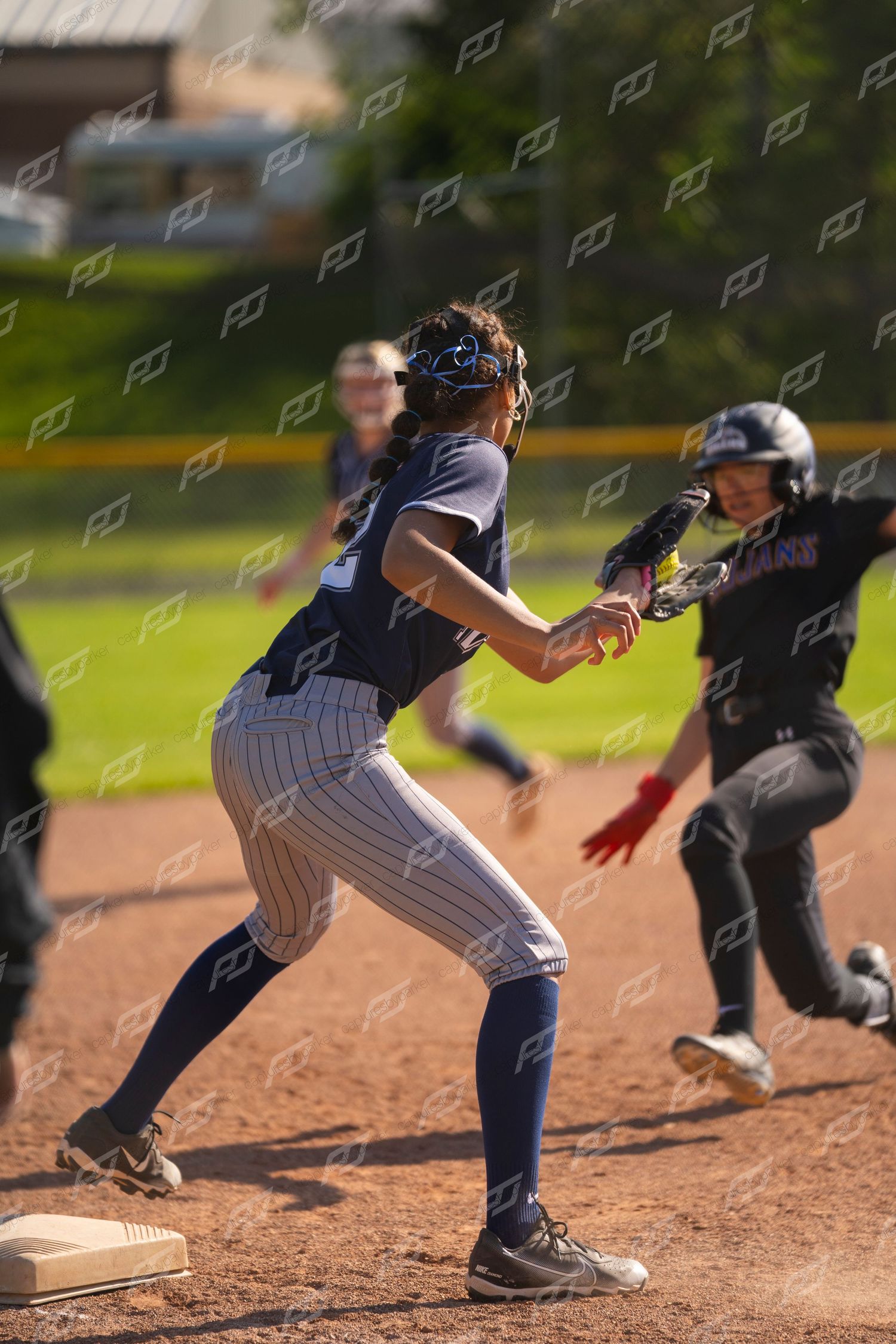 Female softball fielder tags out an opposing baserunner near first base during a game.