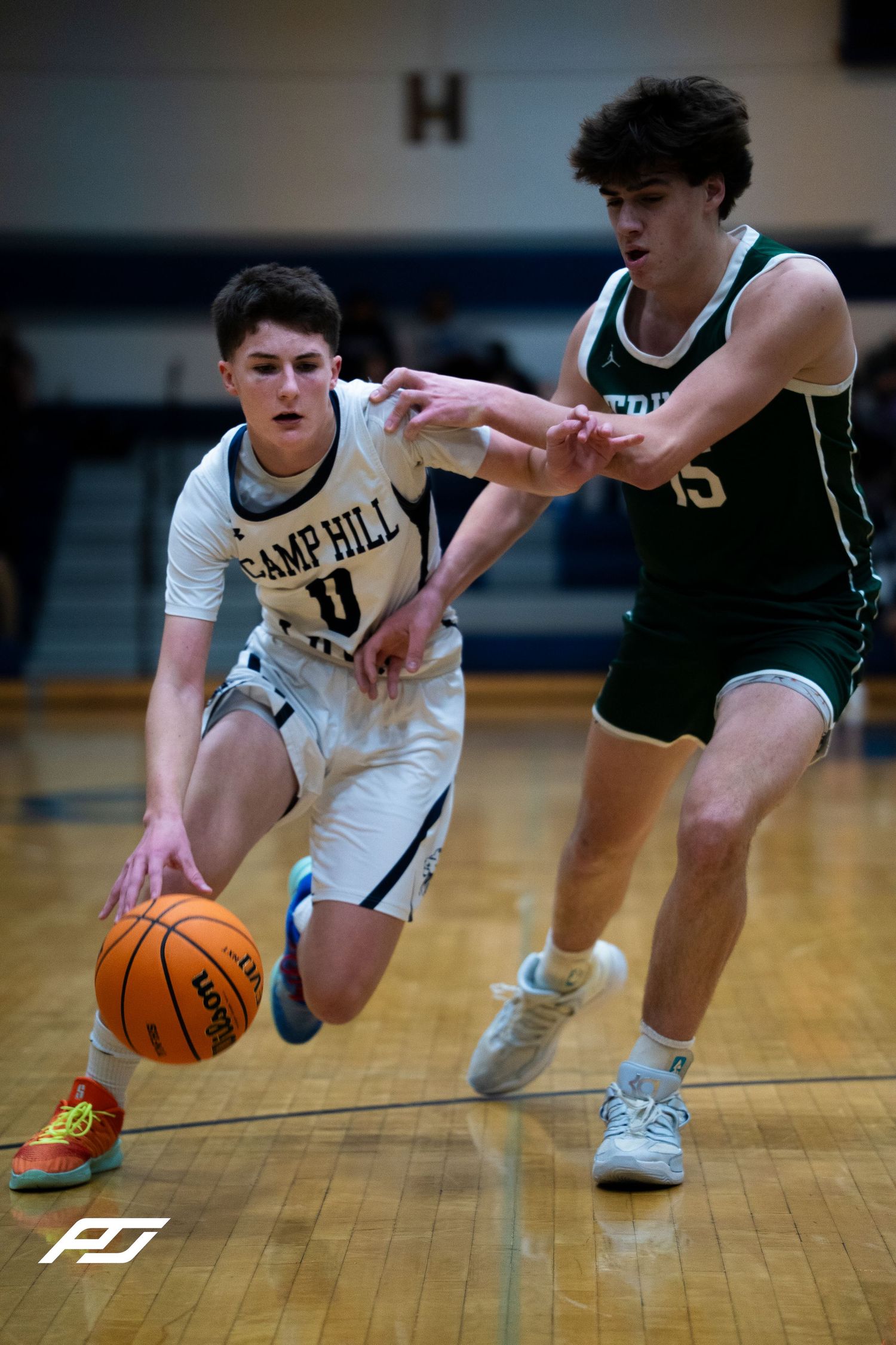 Camp Hill Lions player 0 drives past a Trinity defender during a basketball game.