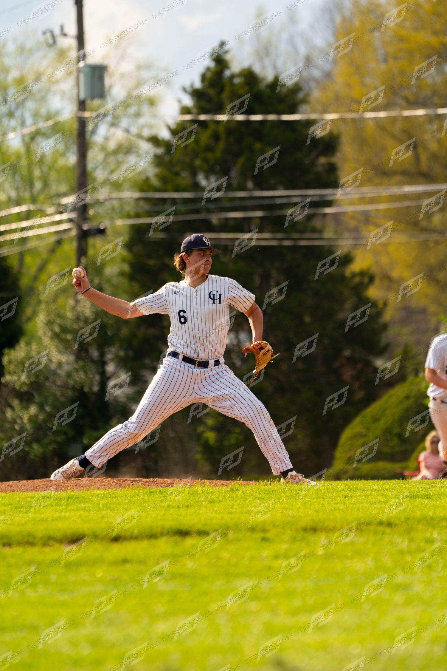 Baseball pitcher in pinstripe uniform number 6 winding up for a pitch on the field.