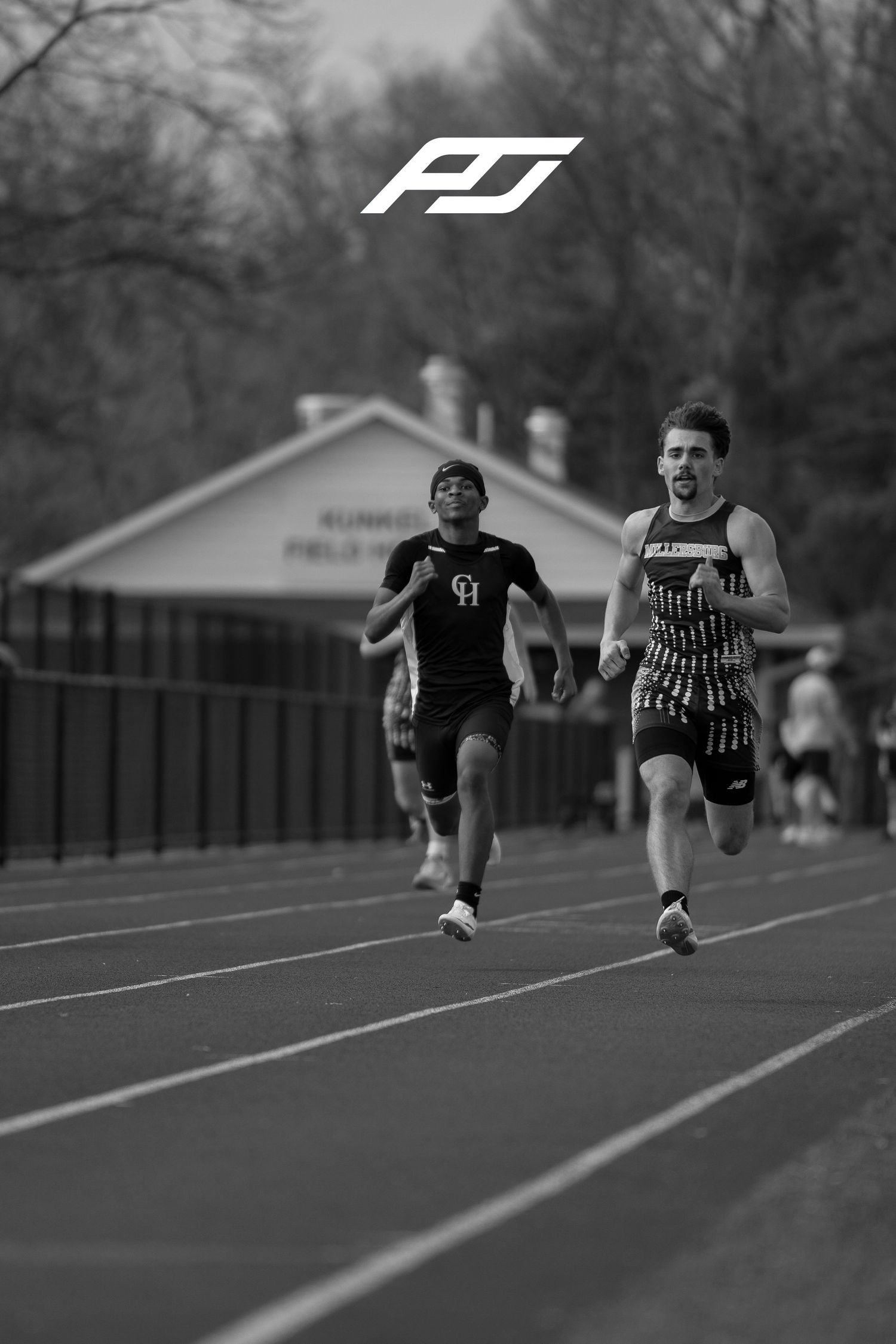 Two male sprinters race down track in black and white photo at outdoor track meet.
