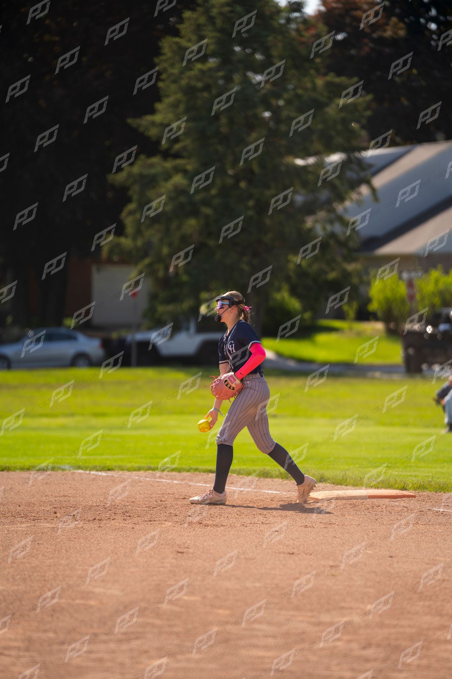 Female softball pitcher stands on the mound preparing to deliver a pitch.