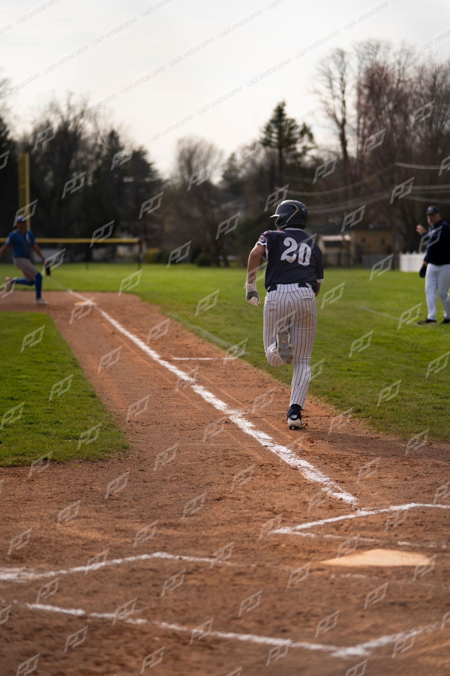 Baseball player #20 in pinstripe uniform runs down the baseline during a youth baseball game.