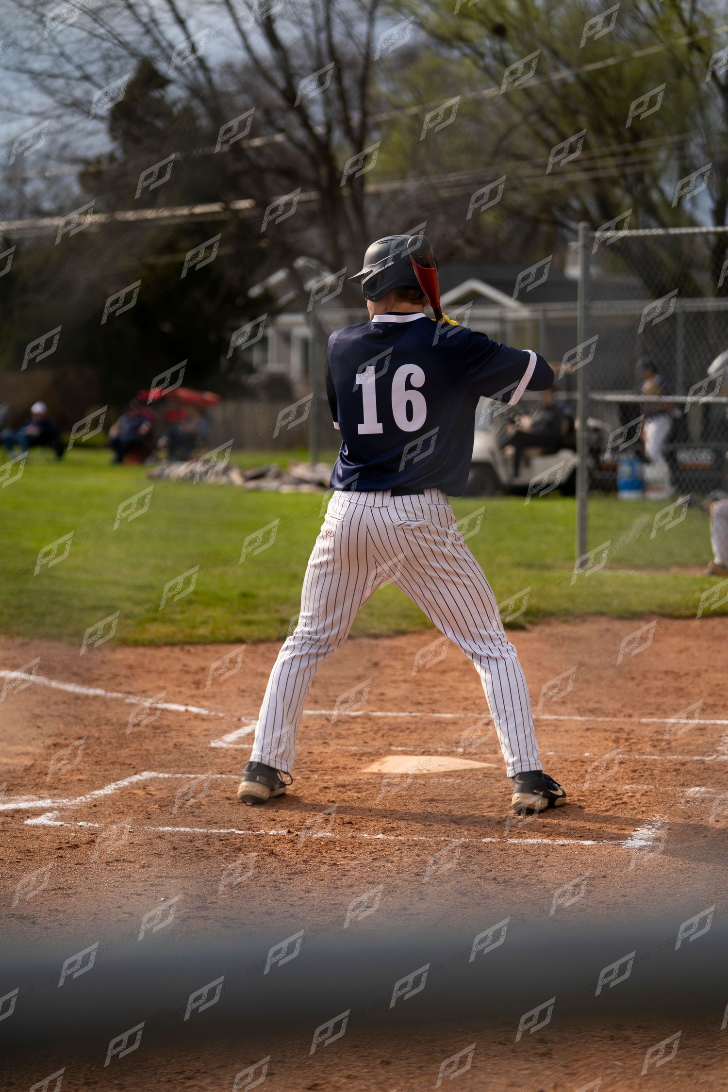 Baseball player #16 in navy pinstripe uniform stands in batting stance at home plate.