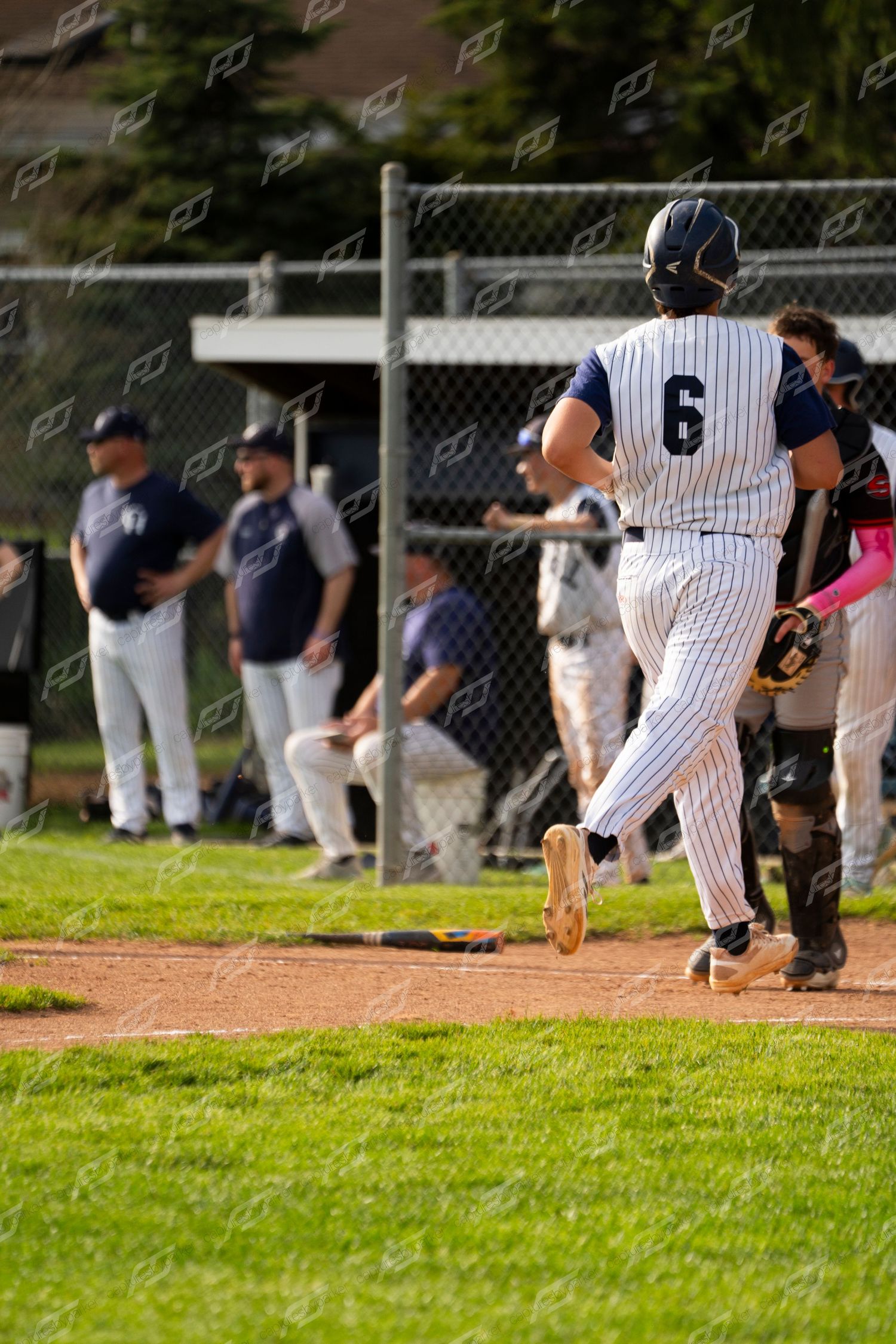 Baseball player #6 in pinstripe uniform runs toward home plate during a competitive youth baseball game.