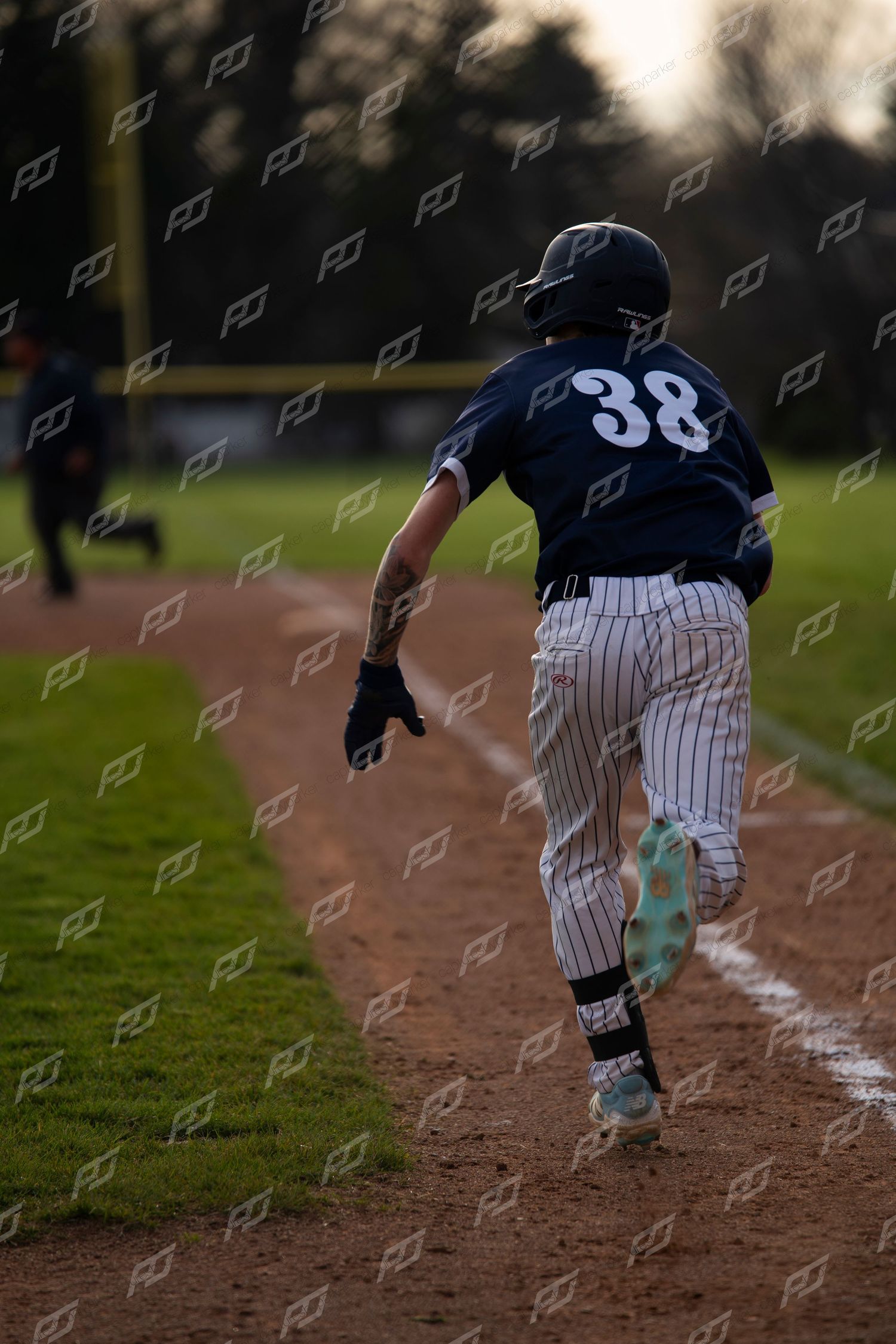 Baseball player #38 runs the baseline wearing teal cleats during an outdoor game.