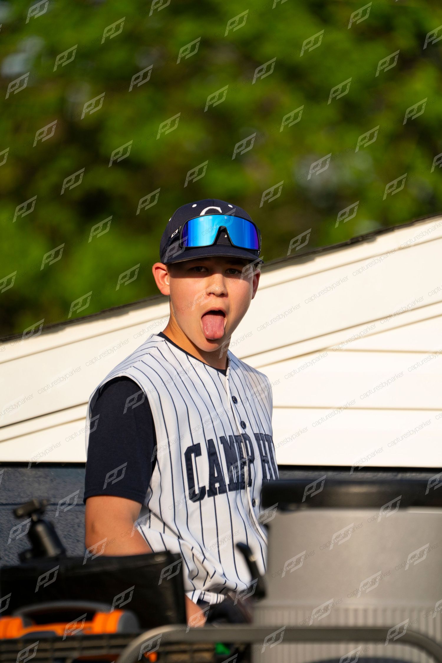 Camp Hill baseball player makes a funny face with tongue out wearing blue mirrored sunglasses.