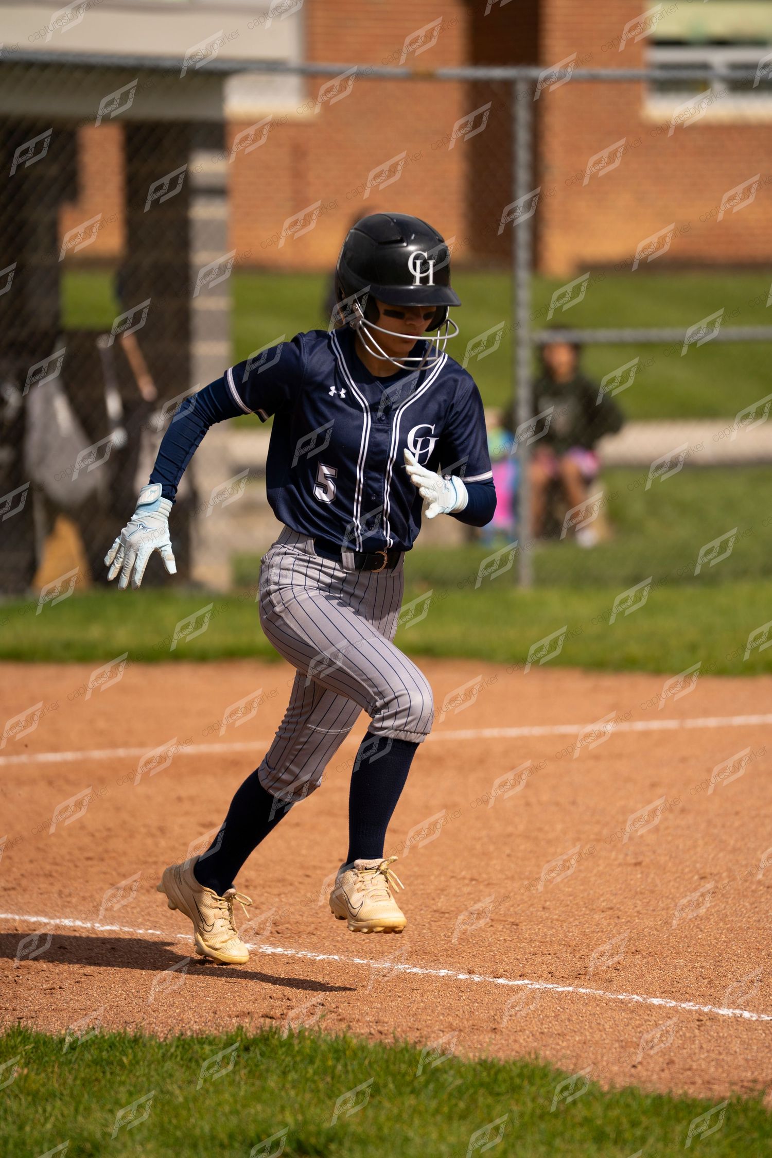 Softball player #5 sprints from home plate after hitting during game.