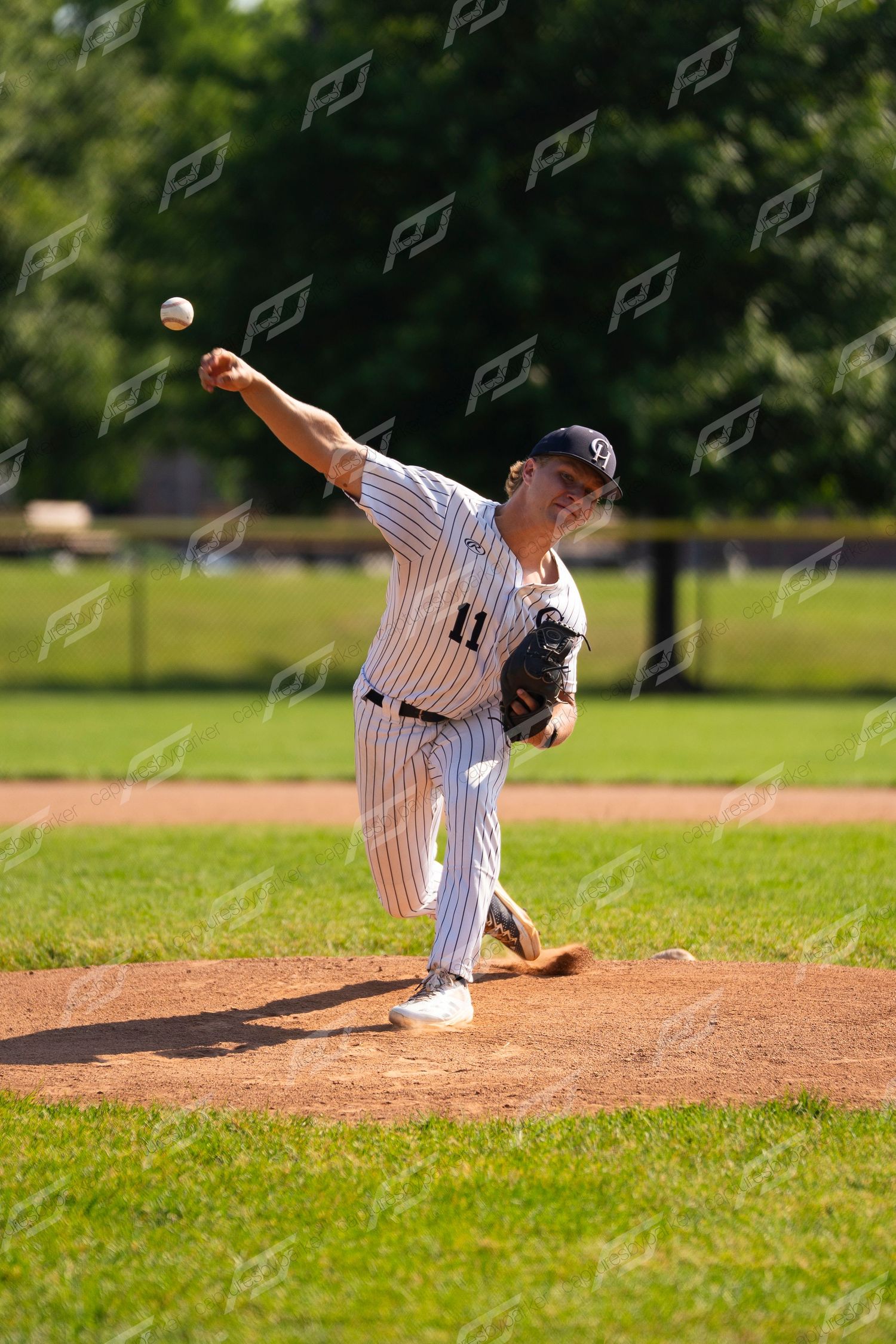 Baseball pitcher #11 in pinstripe uniform delivering a pitch from the mound during a sunny game.