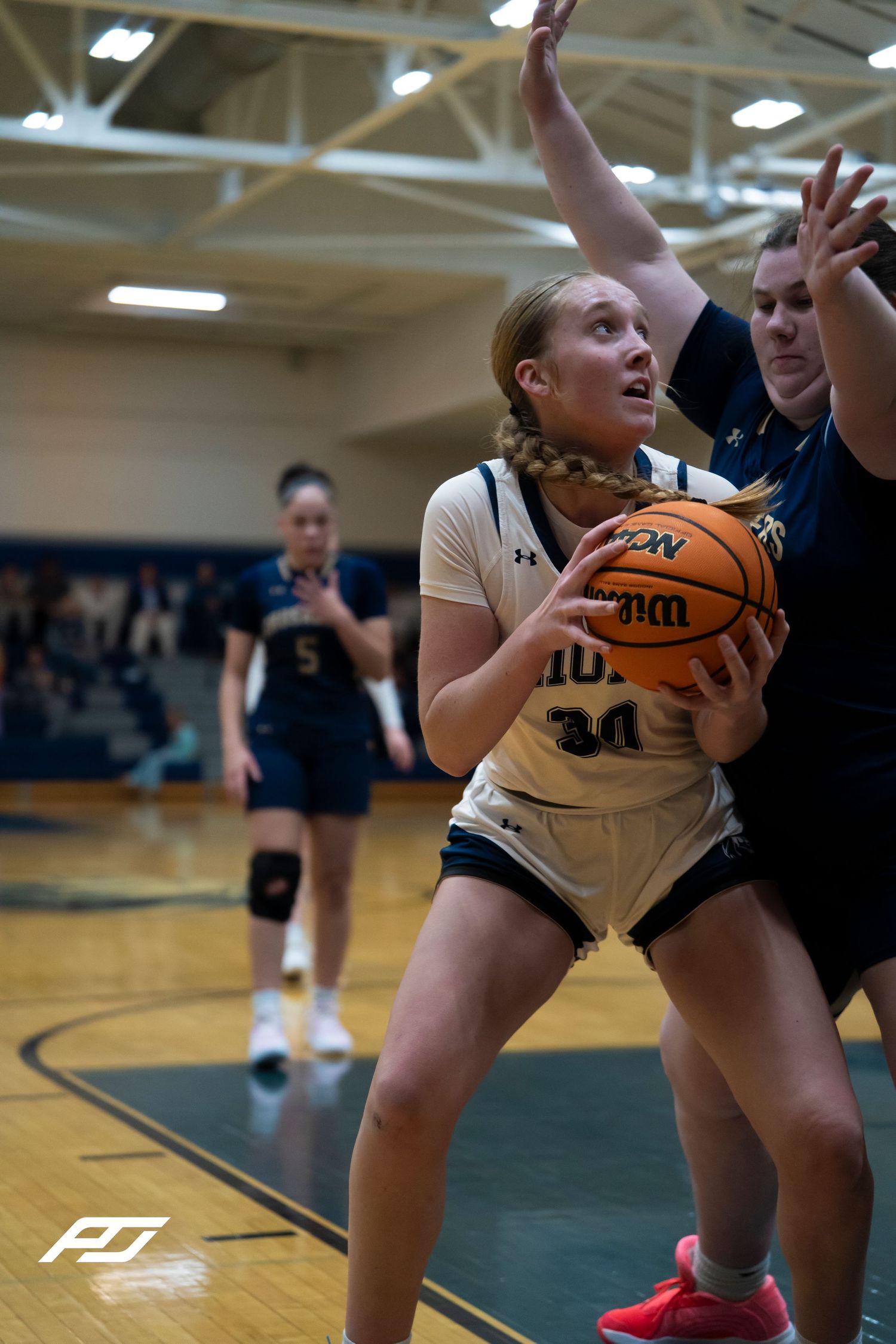Lions number 34 looks to score in the post while being defended during a girls basketball game.