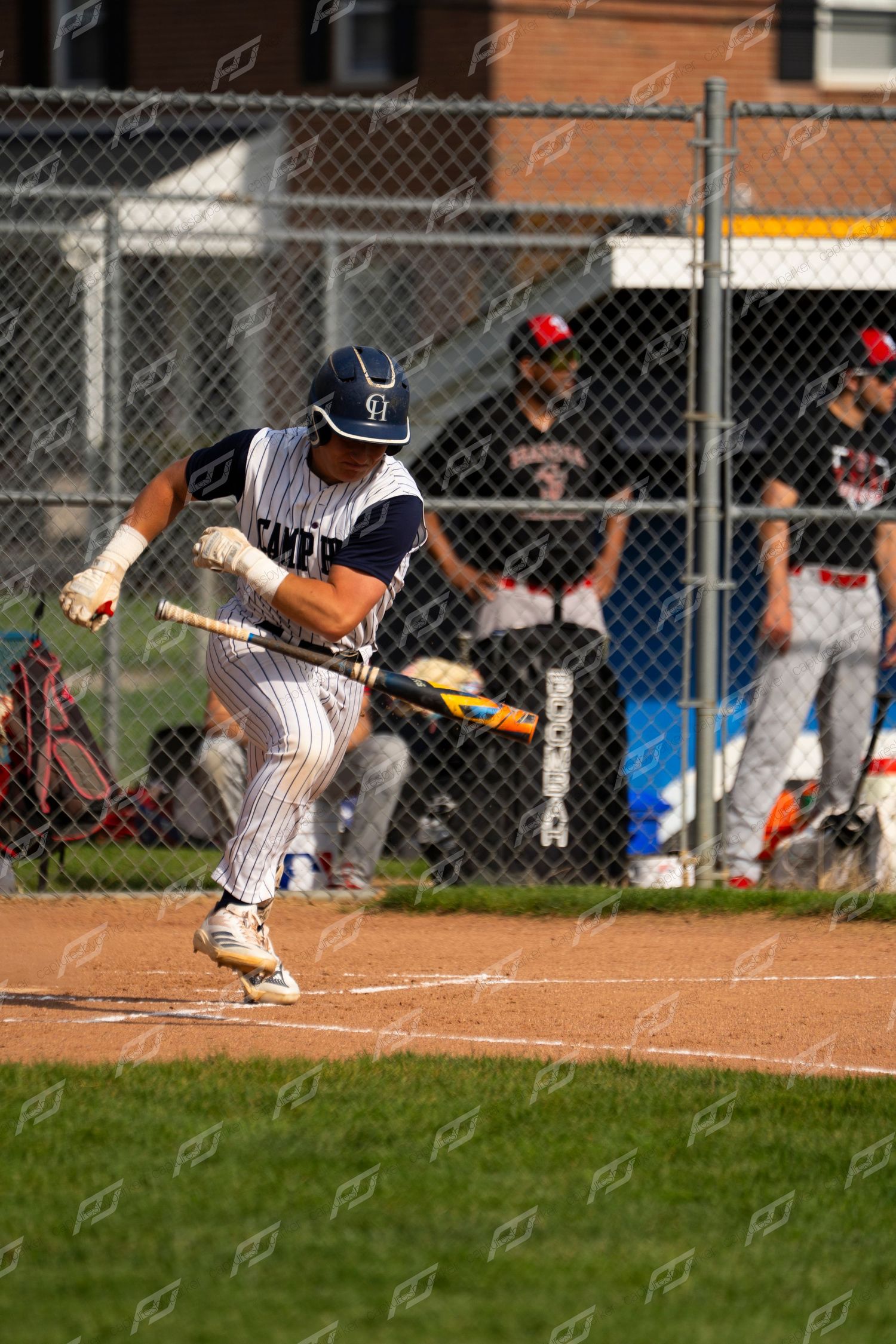 Camp Hill batter swings at a pitch during a baseball game with dugout players watching.