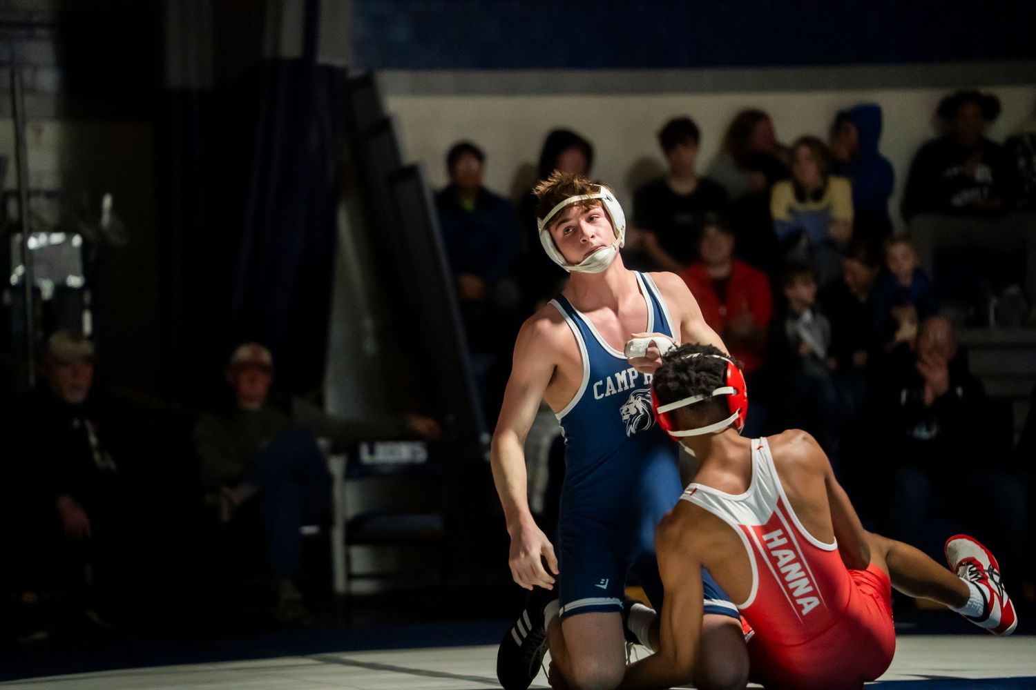 Wrestler in blue Camp Hill singlet lifts opponent during a competitive high school wrestling match.