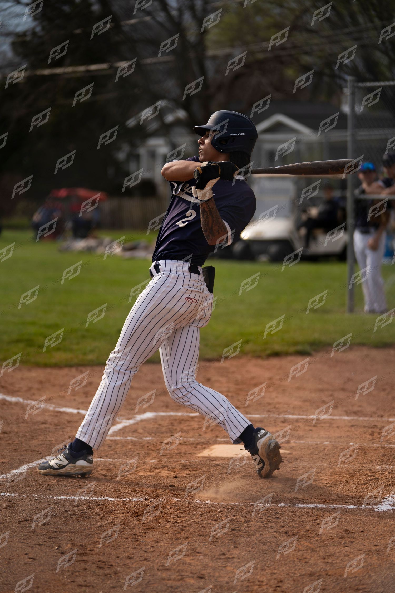 Baseball player in navy pinstripe uniform swinging bat at home plate during a game.