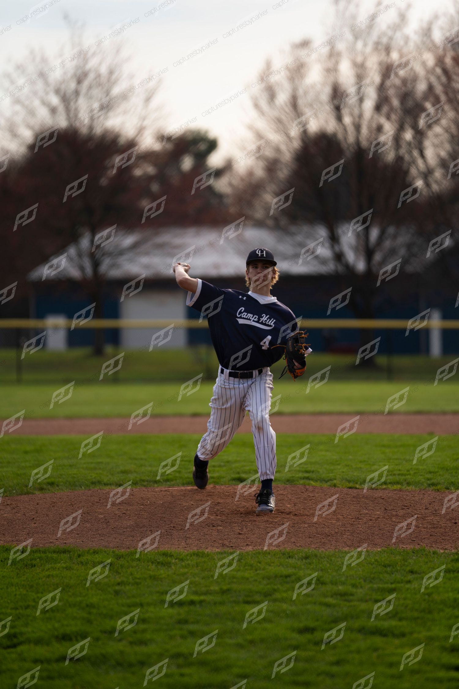 Baseball pitcher #4 winds up to throw on the mound during an outdoor game.