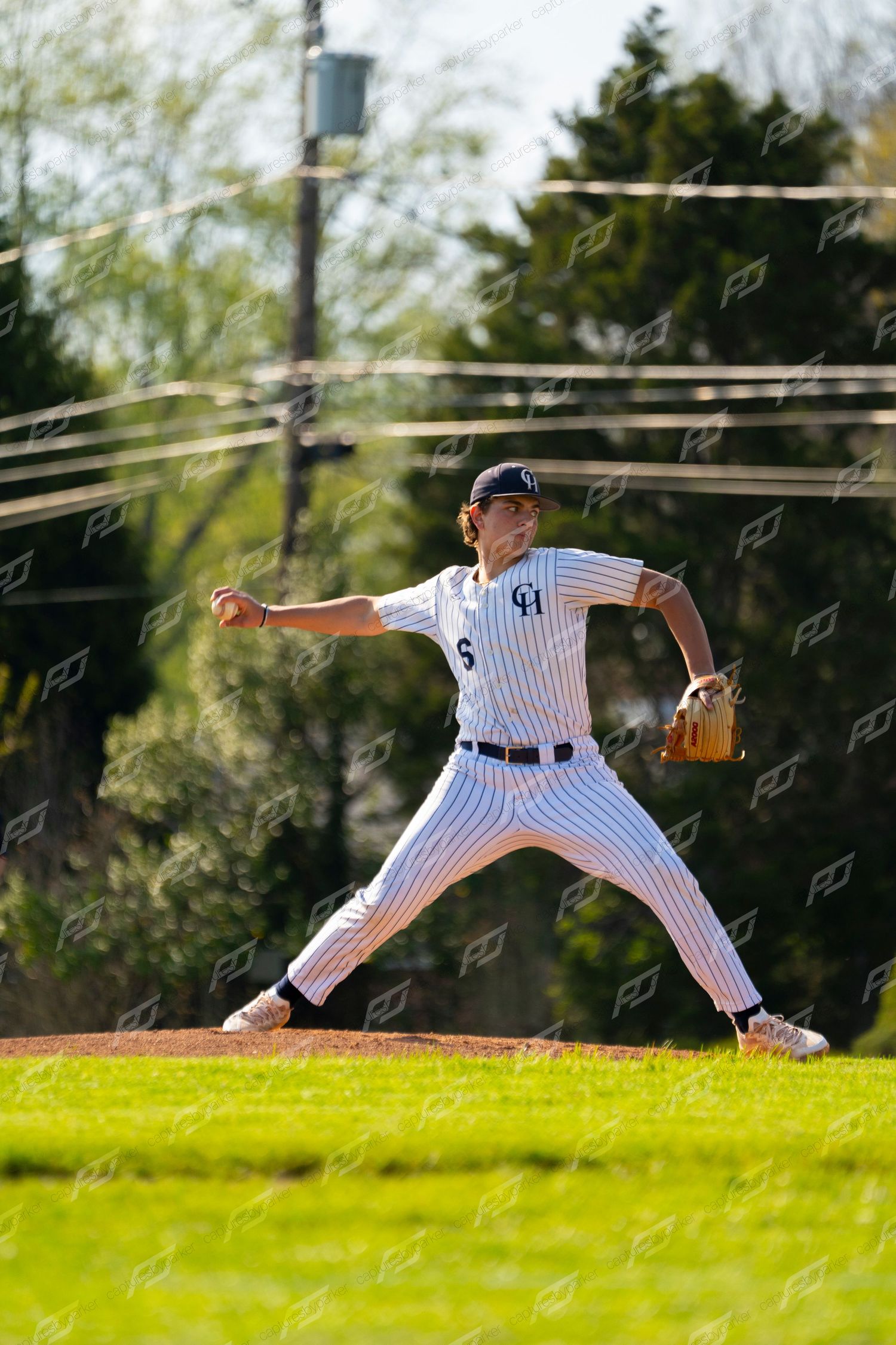 Baseball pitcher #5 in white pinstripe uniform delivers a pitch on a sunny outdoor field.