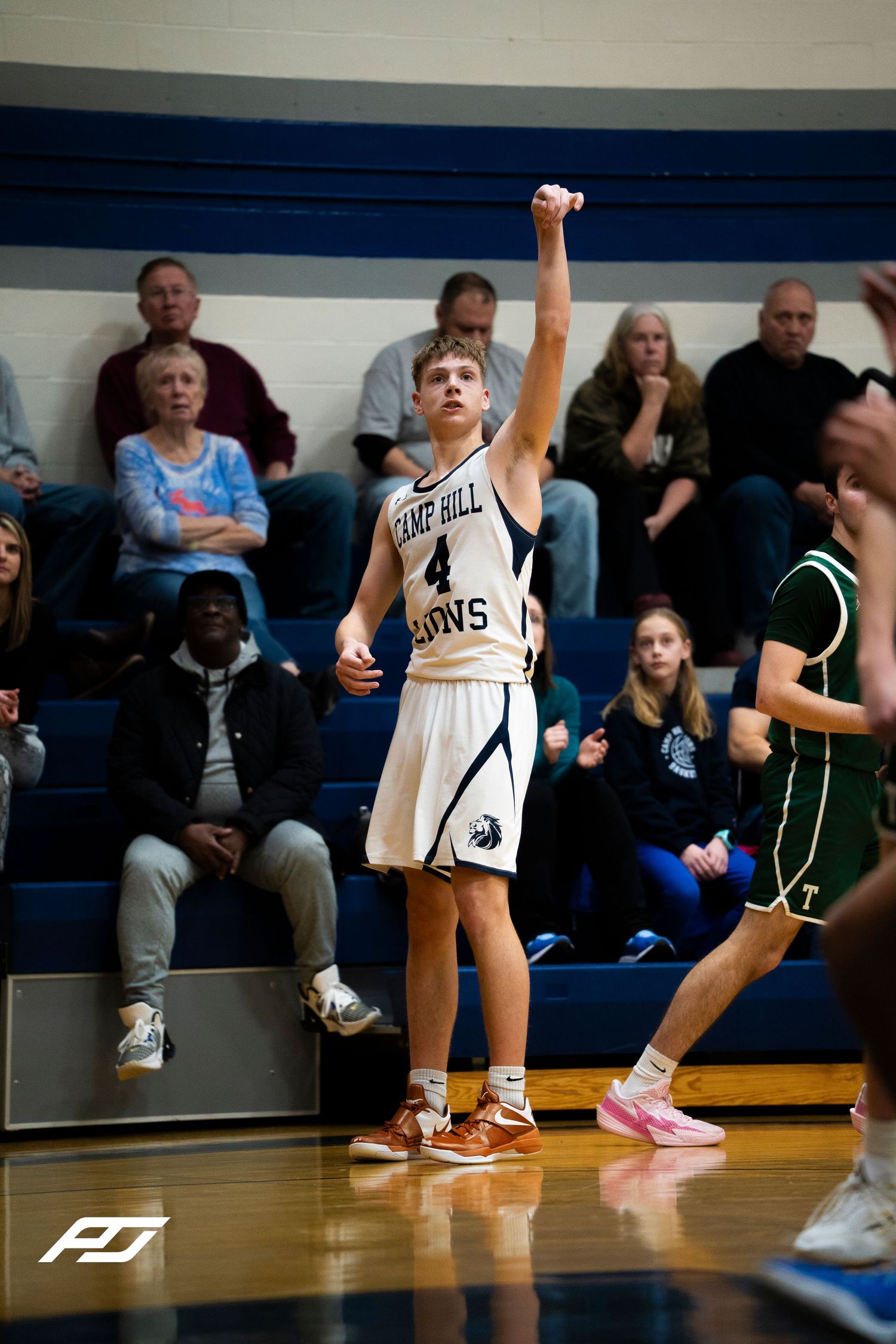 Camp Hill Lions #4 follows through on jump shot with fist raised during high school basketball game.