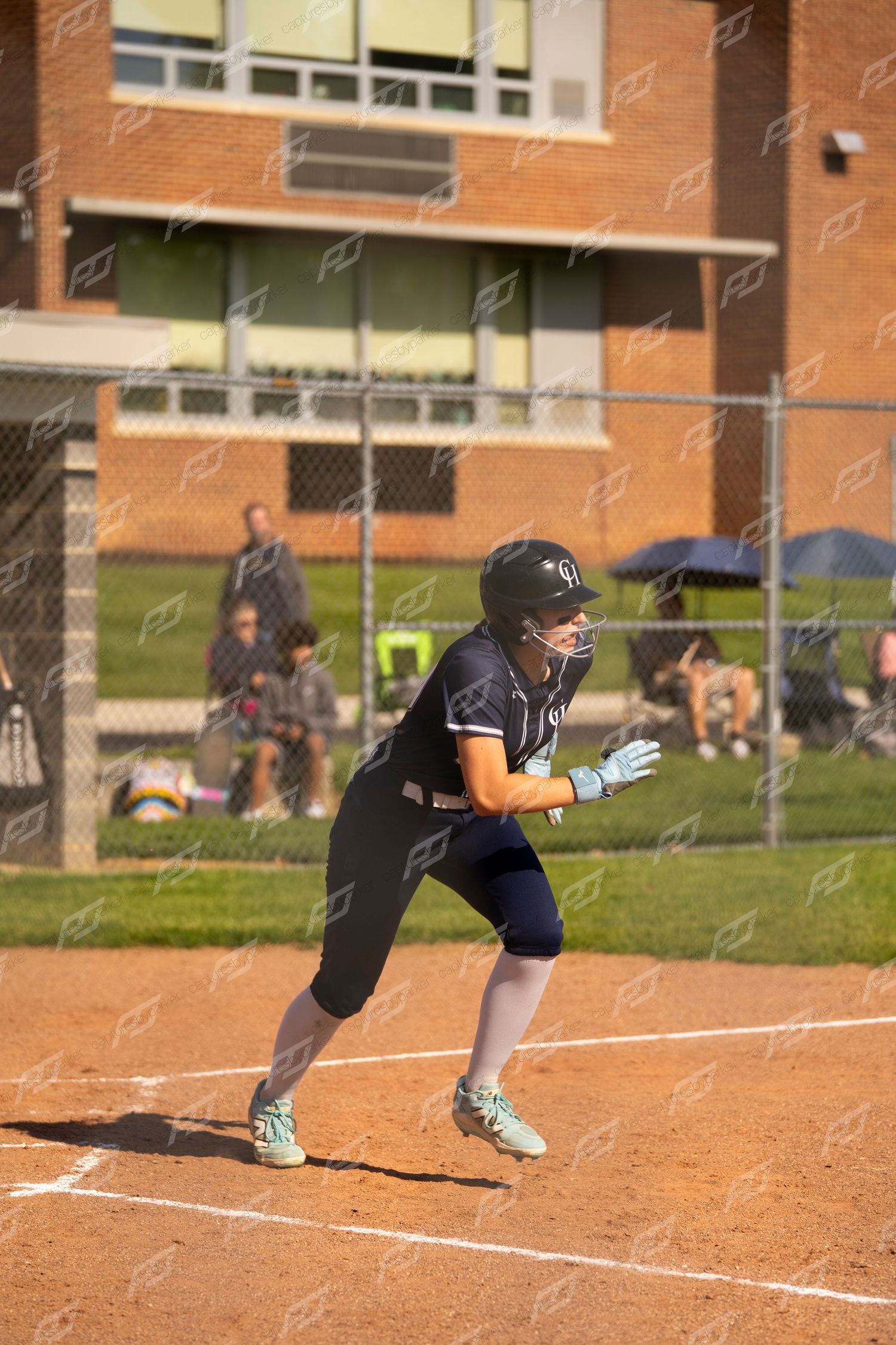 Female softball player in navy uniform sprints from base during an outdoor game.
