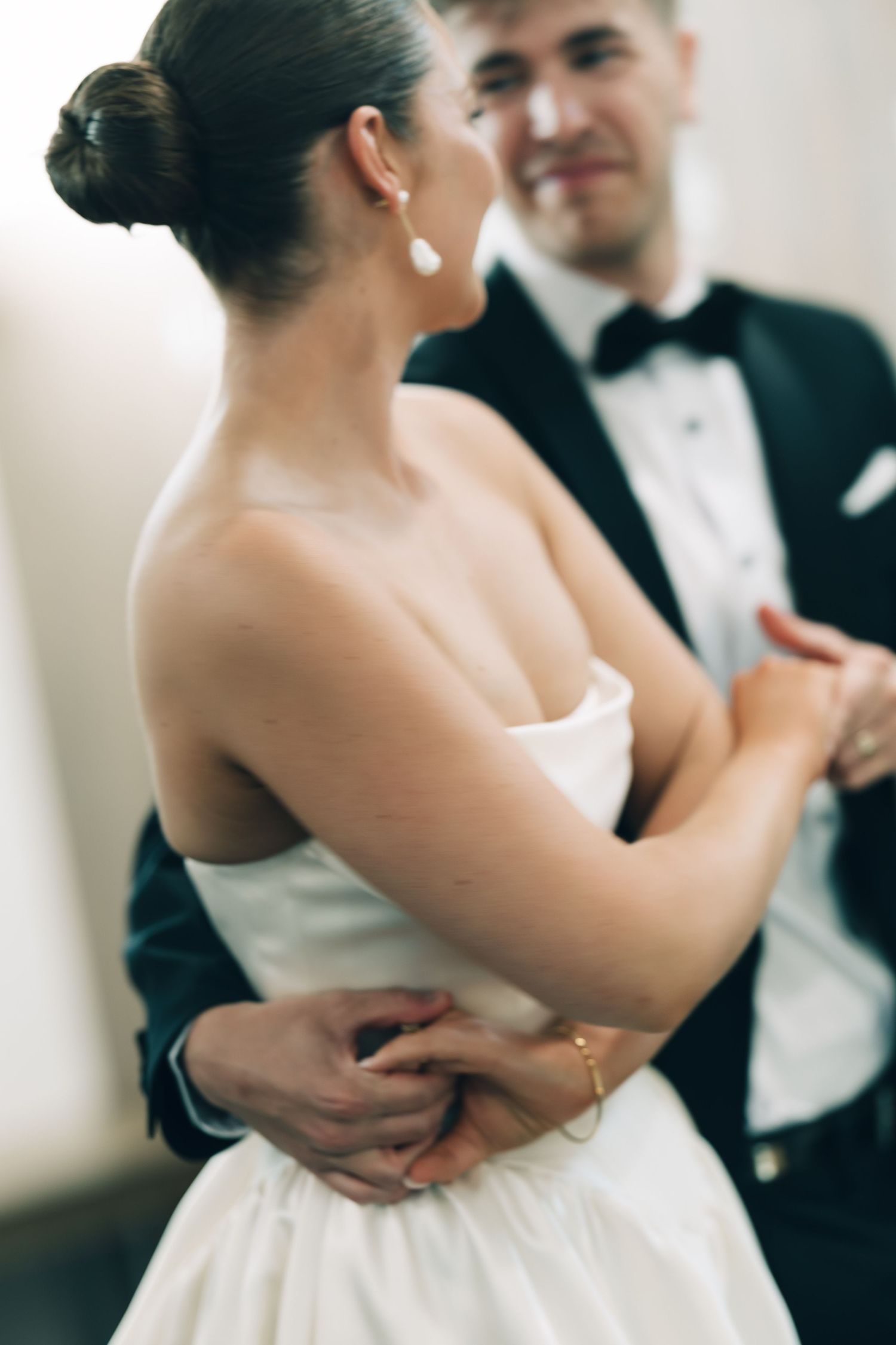 A couple embraces in formal wedding attire during an intimate dance moment.