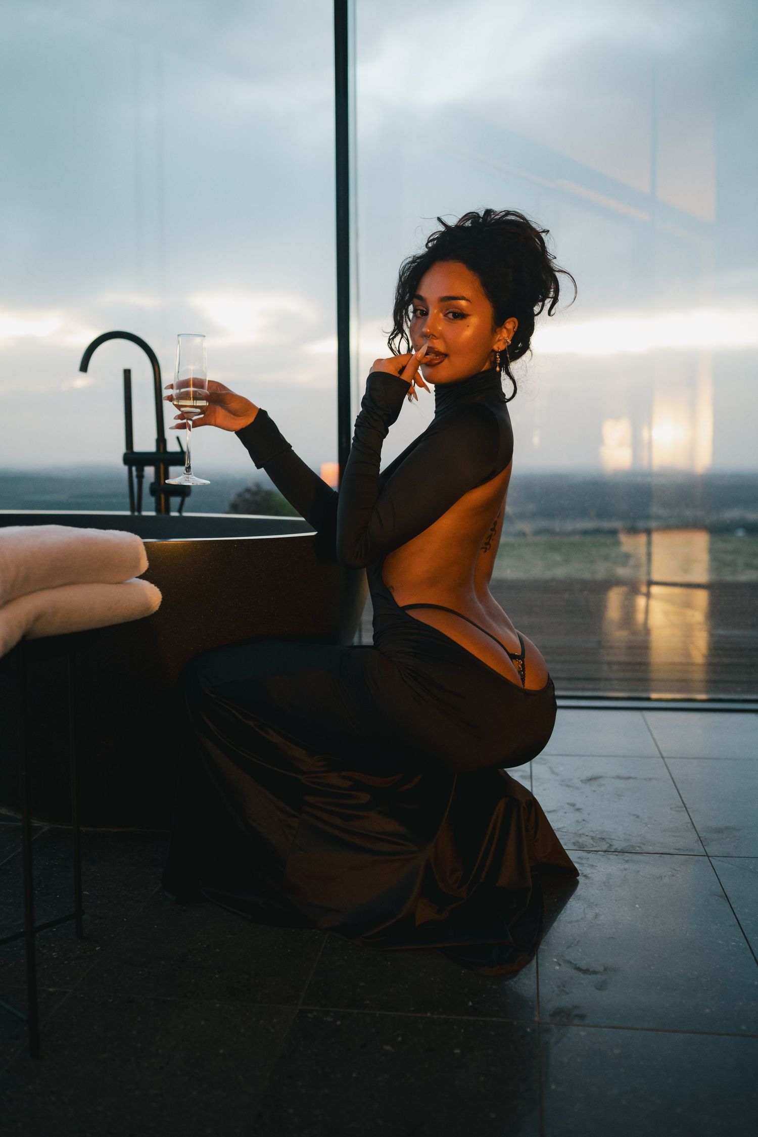 Artistic silhouette photos of a person lounging in dramatic lighting near large windows.