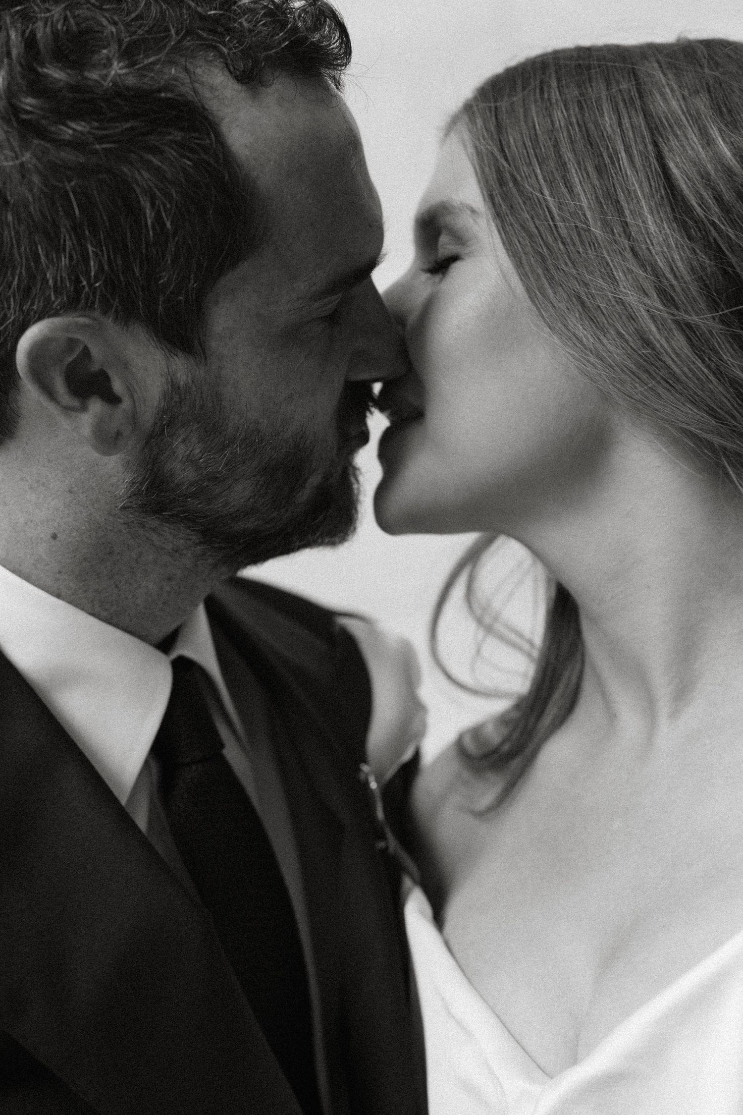 Black and white photo of a bride and groom sharing a romantic almost-kiss on their wedding day.