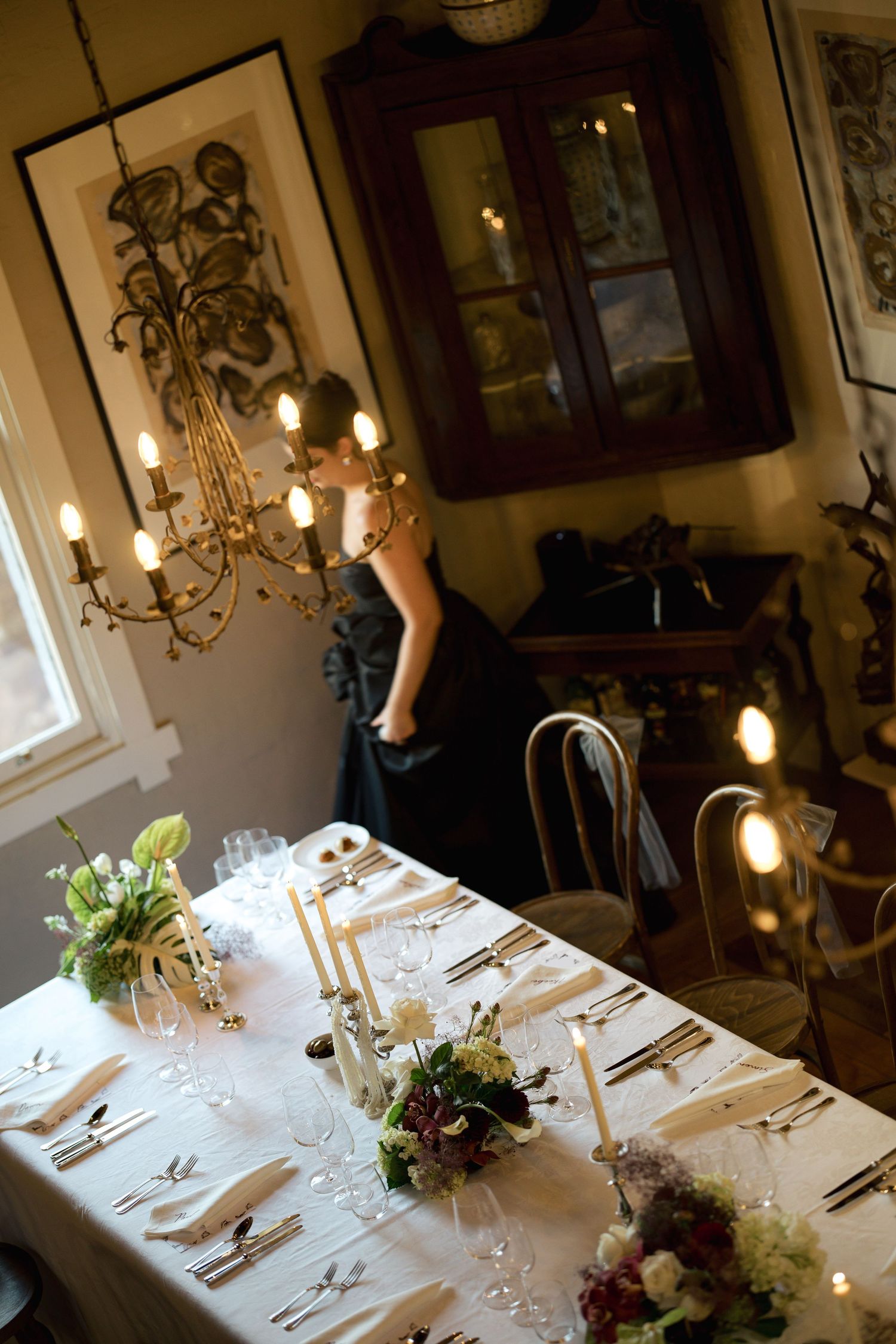 Elegant wedding reception table setting with chandelier and white floral centerpieces.