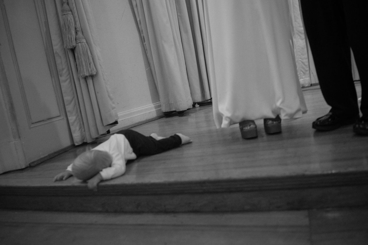 A sequence of black and white photos showing a person falling down in stages on a white floor.