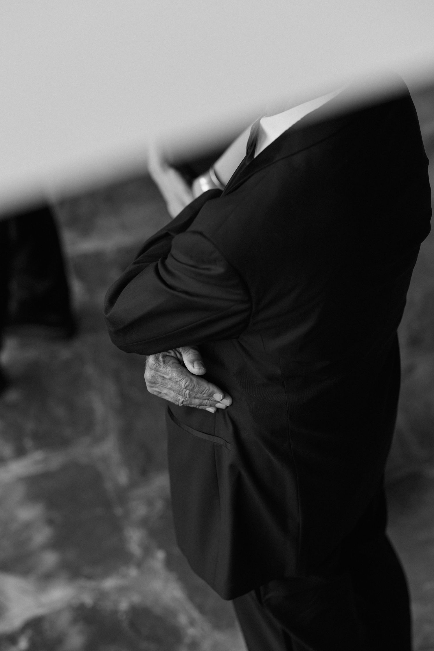 Black and white detail shot of formal attire adjustments during wedding preparations.