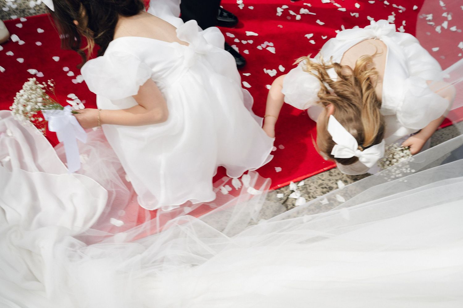 Wedding dress flowing over red carpet steps during celebration.