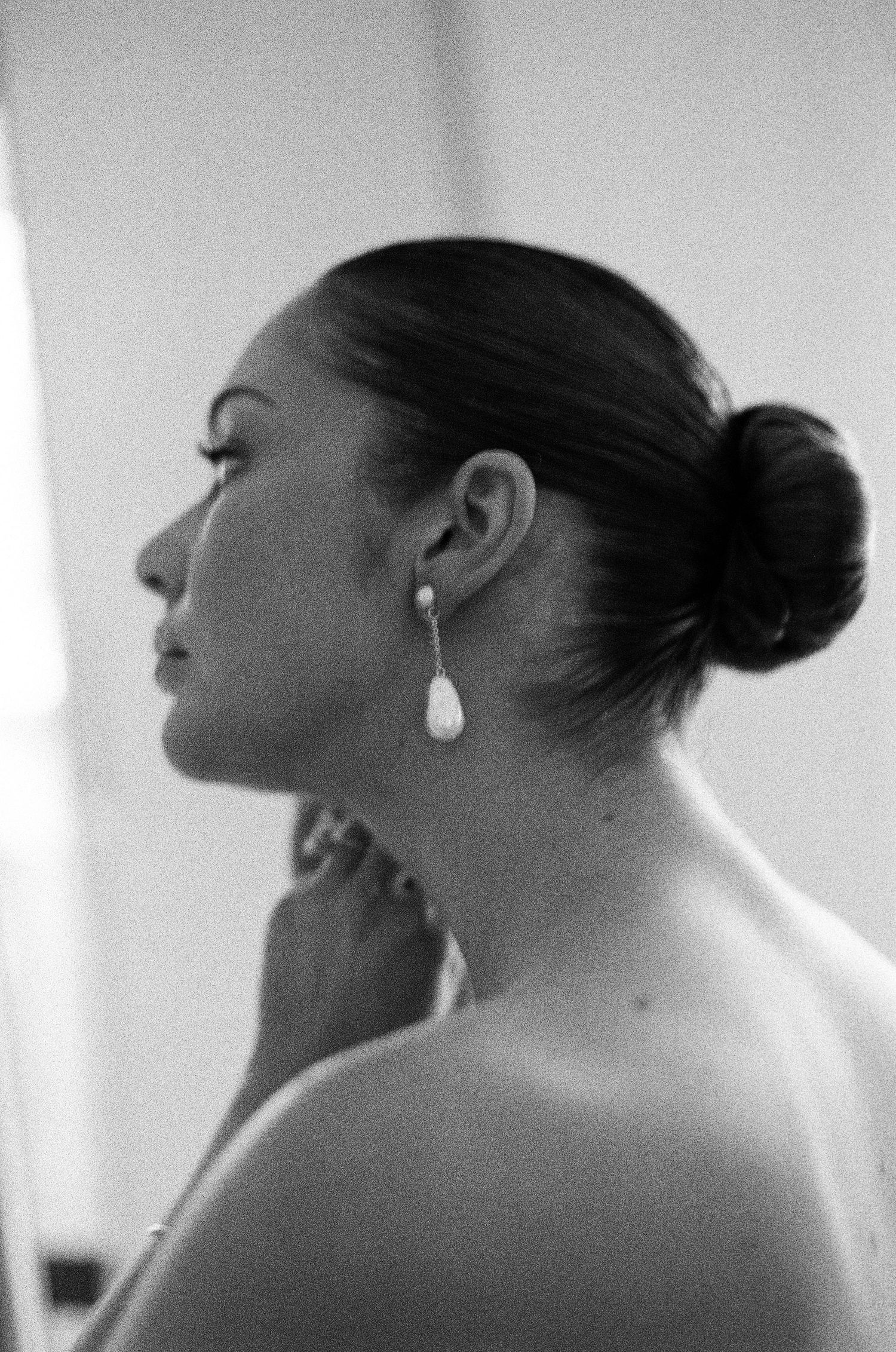 Profile view in black and white showing elegant bridal hairstyle and earrings.