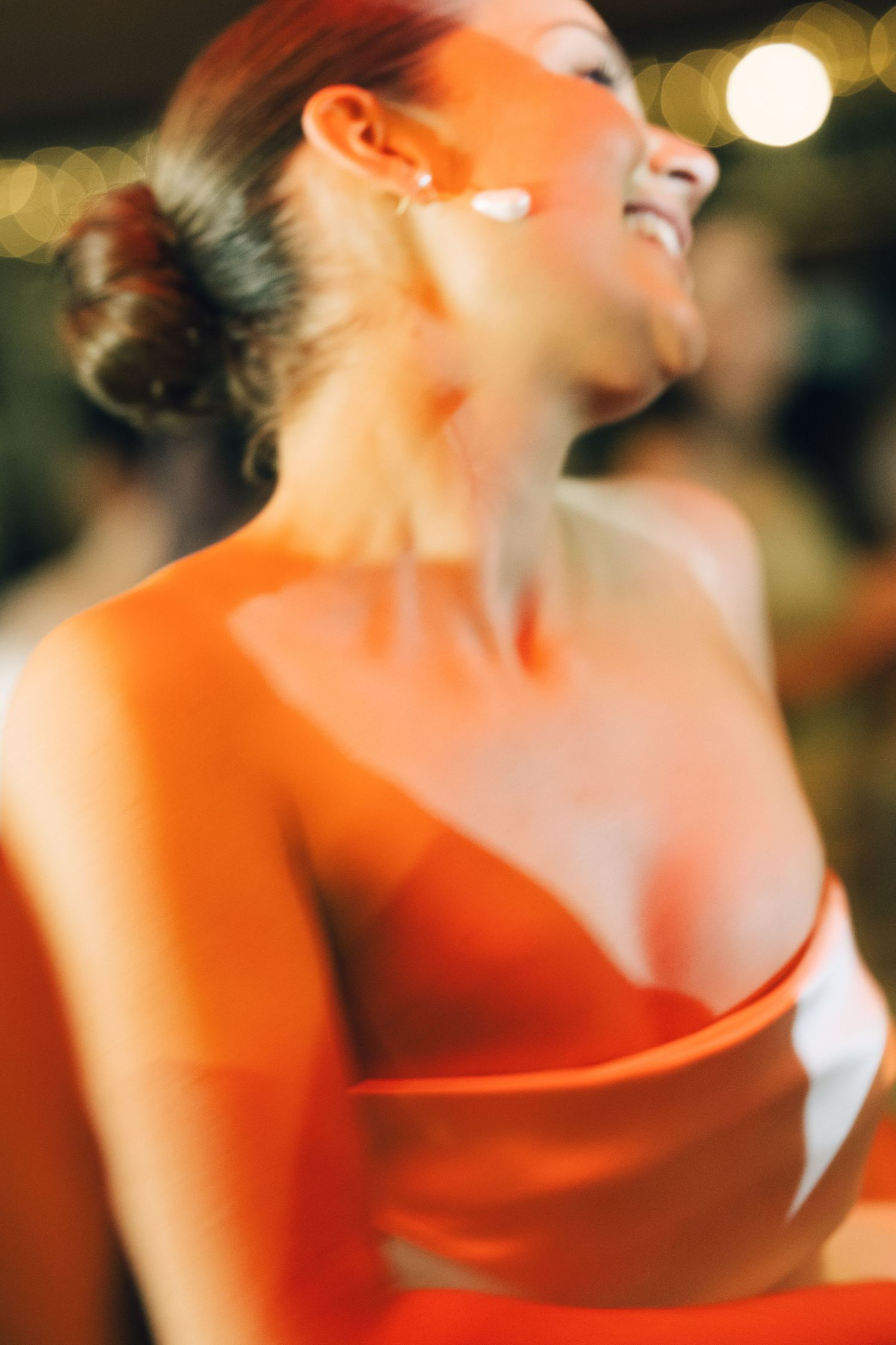 Person in red formal dress laughs during an evening celebration.