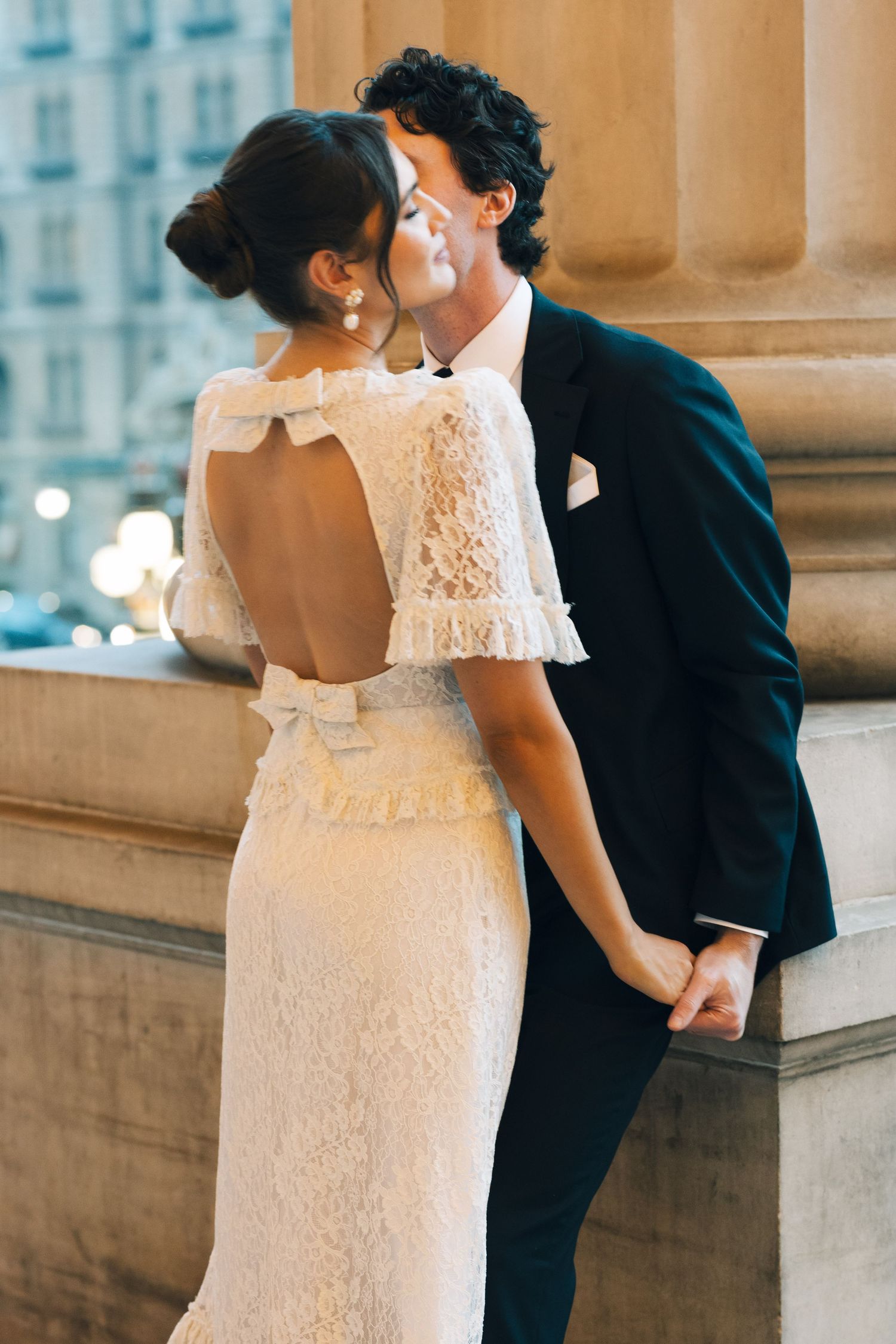 Romantic wedding couple sharing tender moments against classic architectural backdrop.