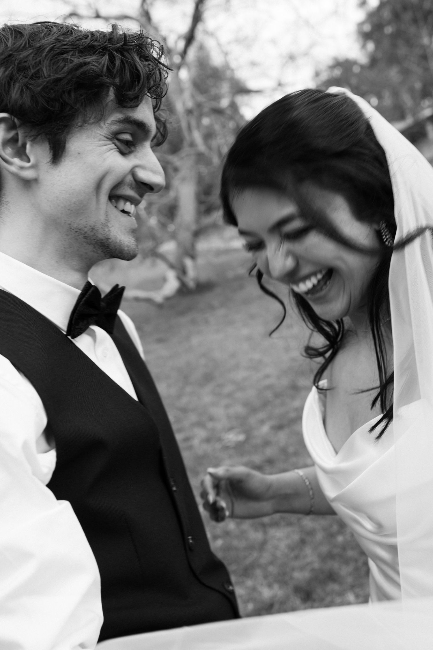 Black and white candid shots capturing joyful laughter between newlyweds outdoors.