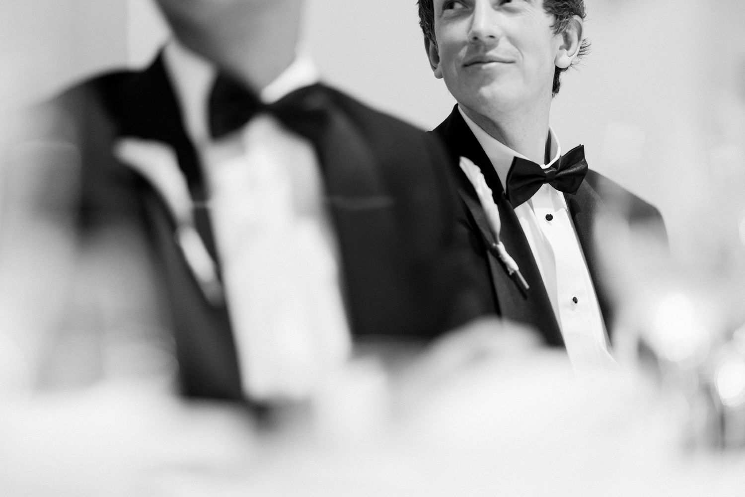 A black and white close-up of formal attire and bow ties at a wedding.
