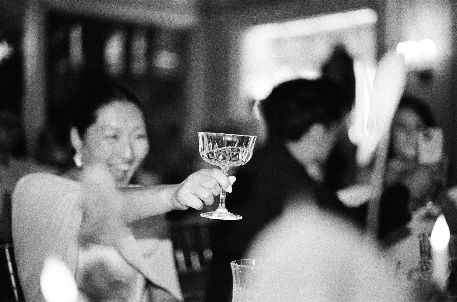 A black and white photograph shows guests enjoying a lively wedding reception celebration.