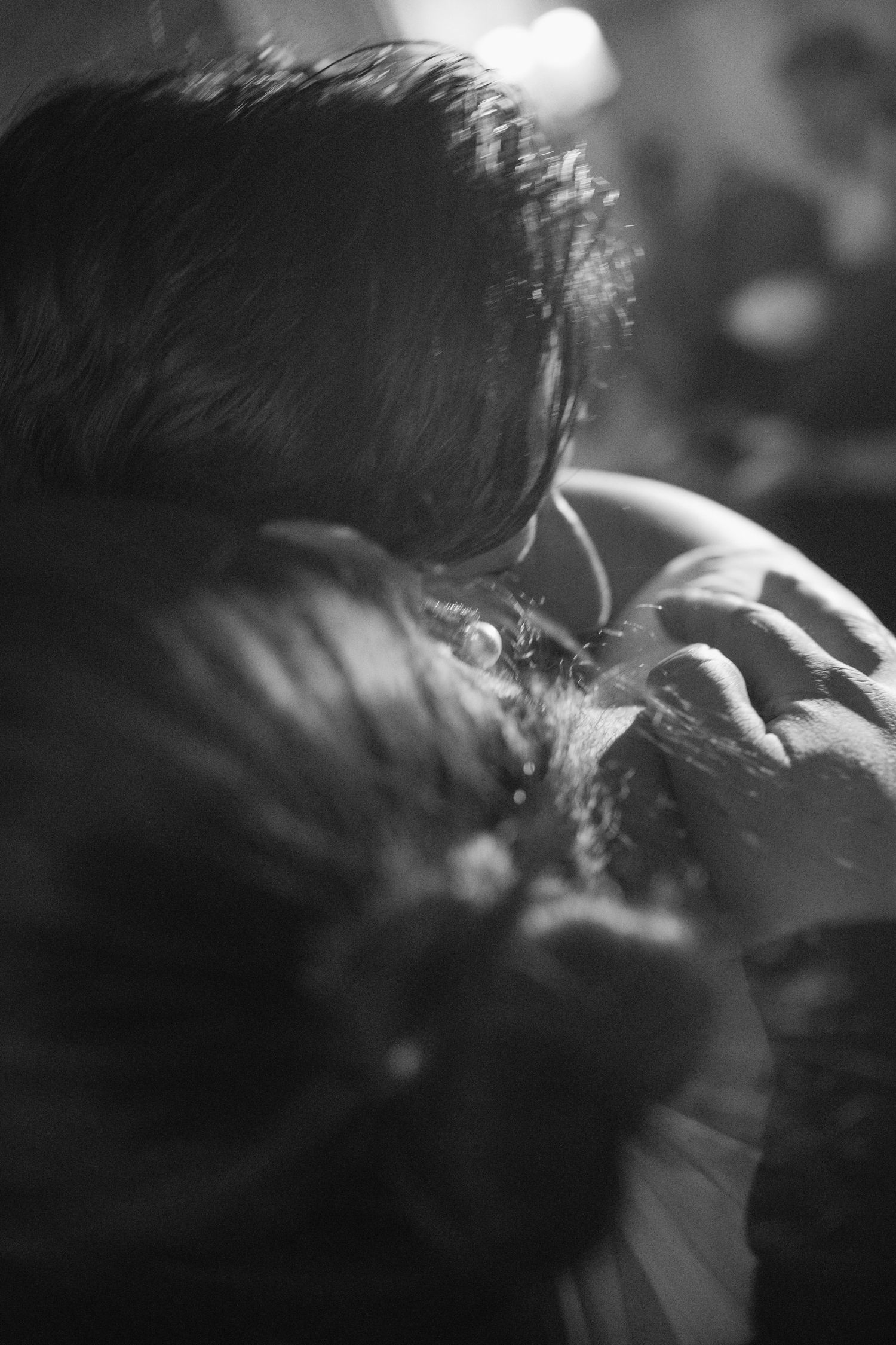 A black and white artistic photograph capturing an intimate close-up moment in soft focus with dramatic lighting.