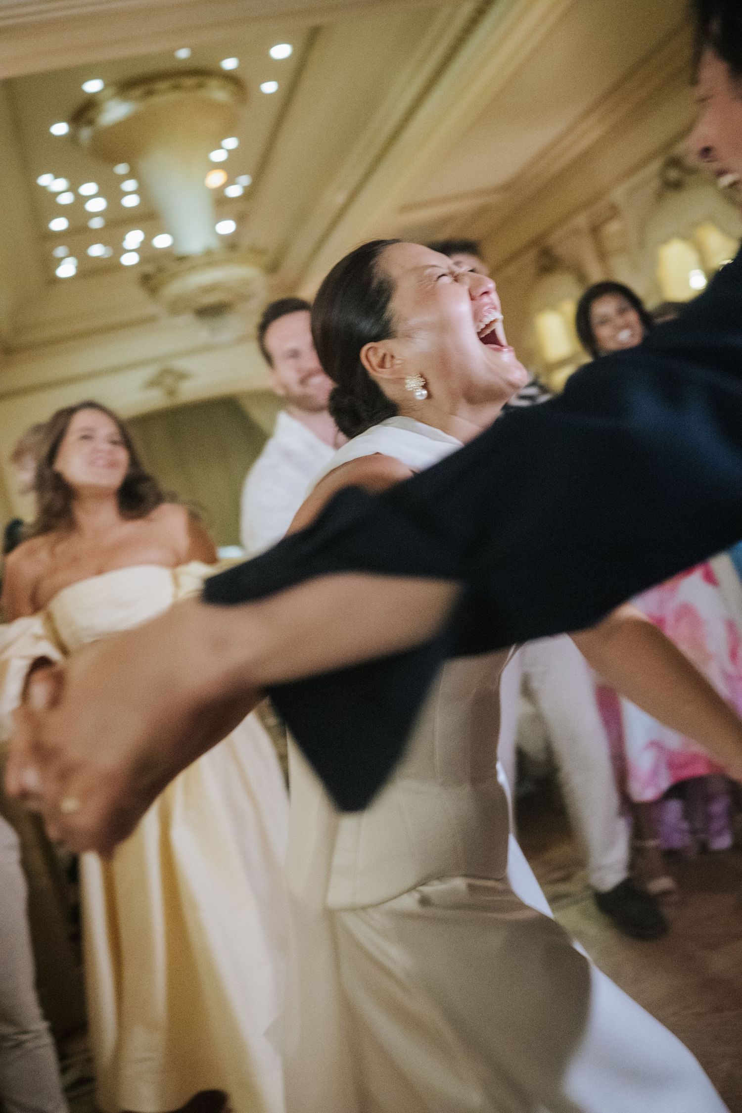 Bride laughing joyfully while dancing with groom at elegant wedding reception ballroom celebration.