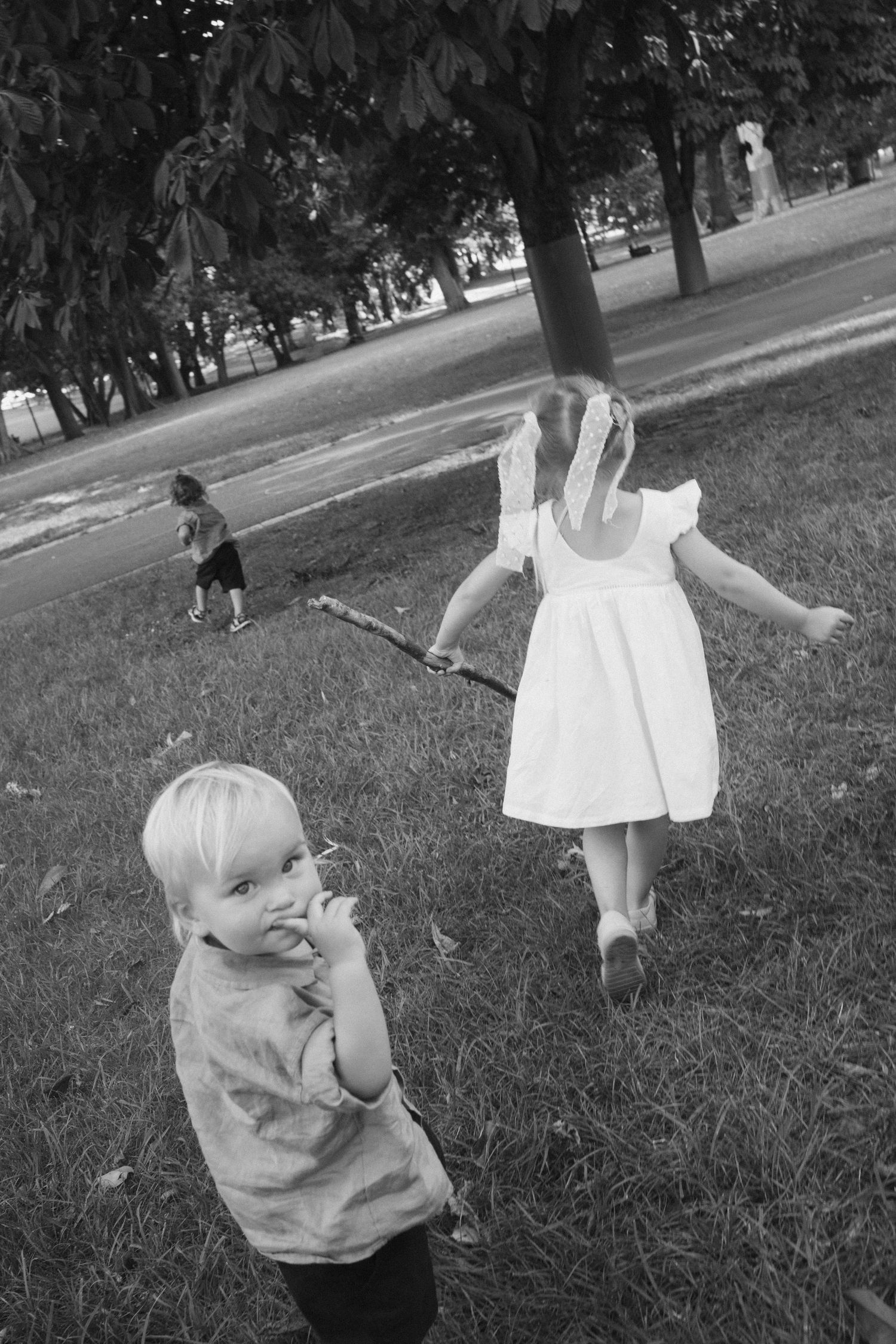 Black and white photo of children playing outdoors in a park on a summer day.