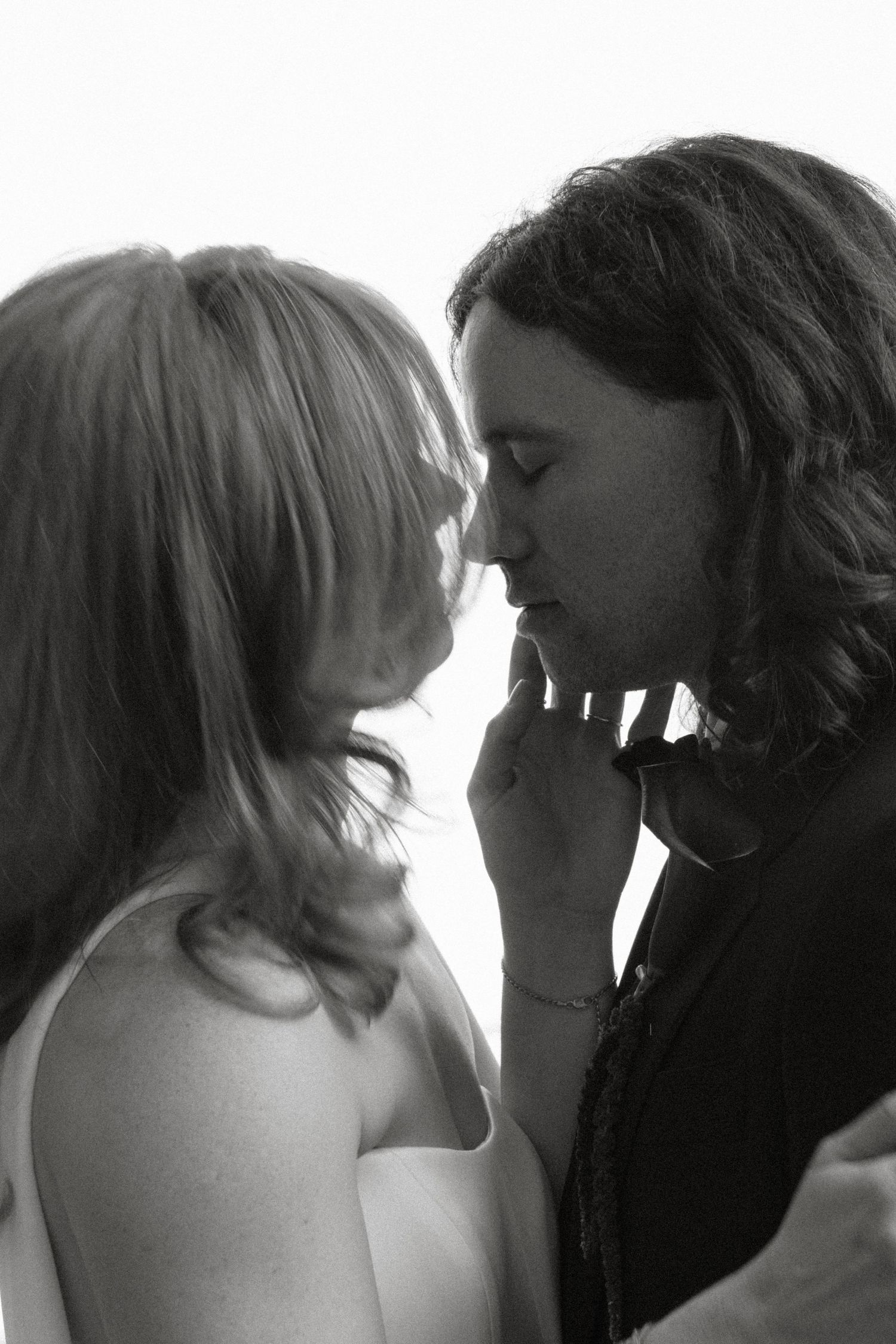 Black and white photo of a couple sharing a romantic kiss, woman with blonde hair and man with long dark hair.