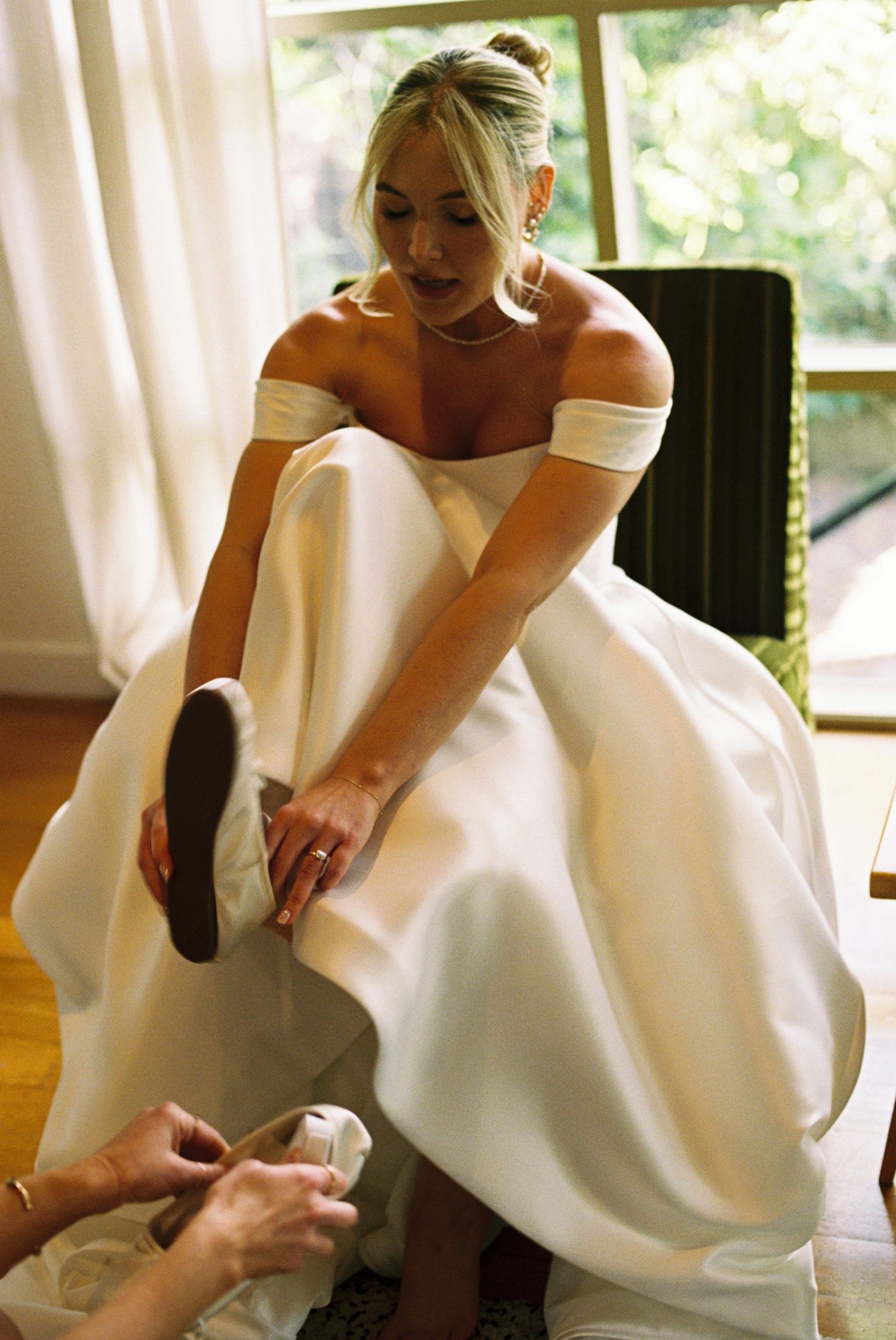 Series showing details of a white wedding dress being adjusted on hardwood floor.
