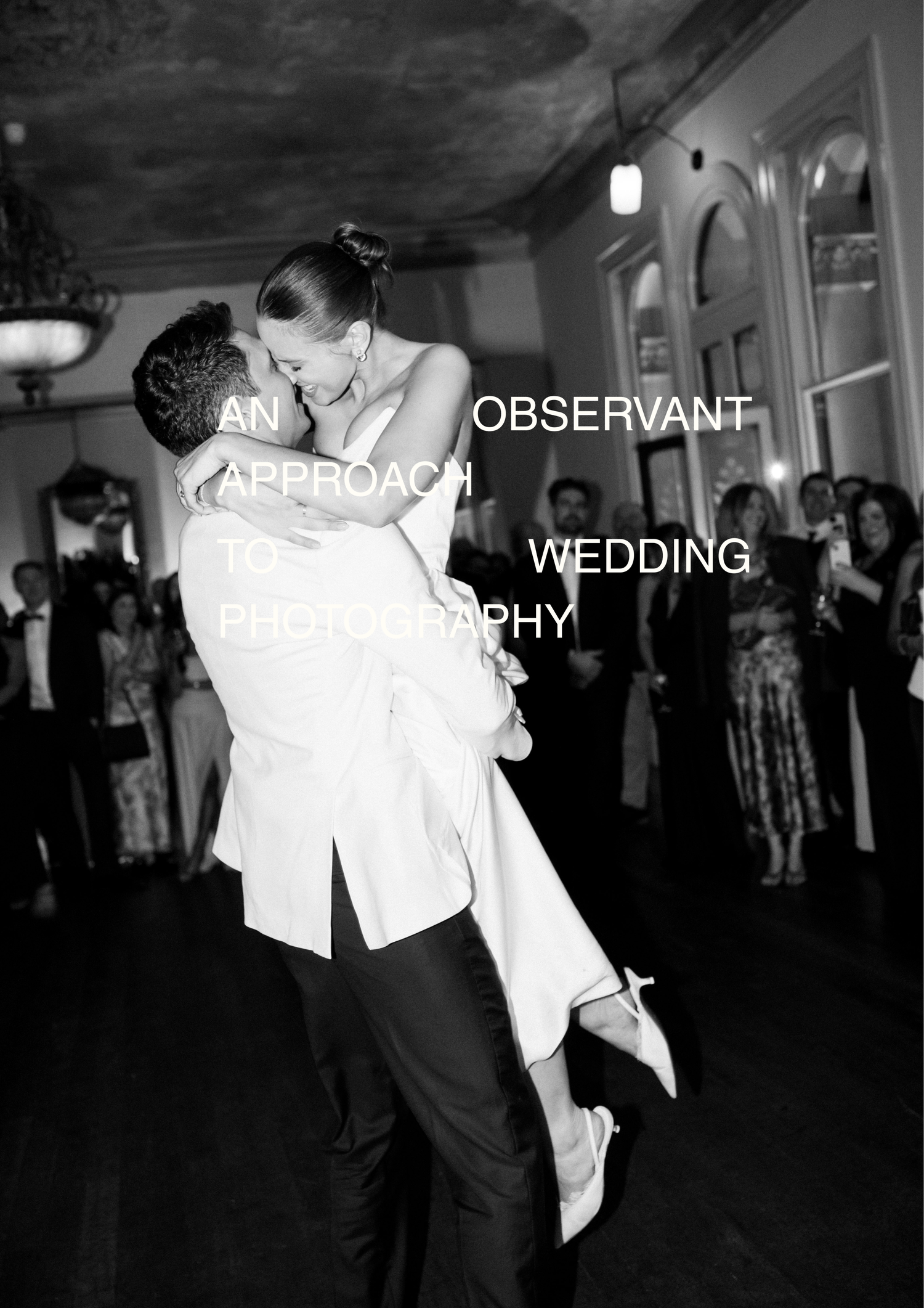 Black and white photo of groom lifting bride during first dance at elegant wedding reception.