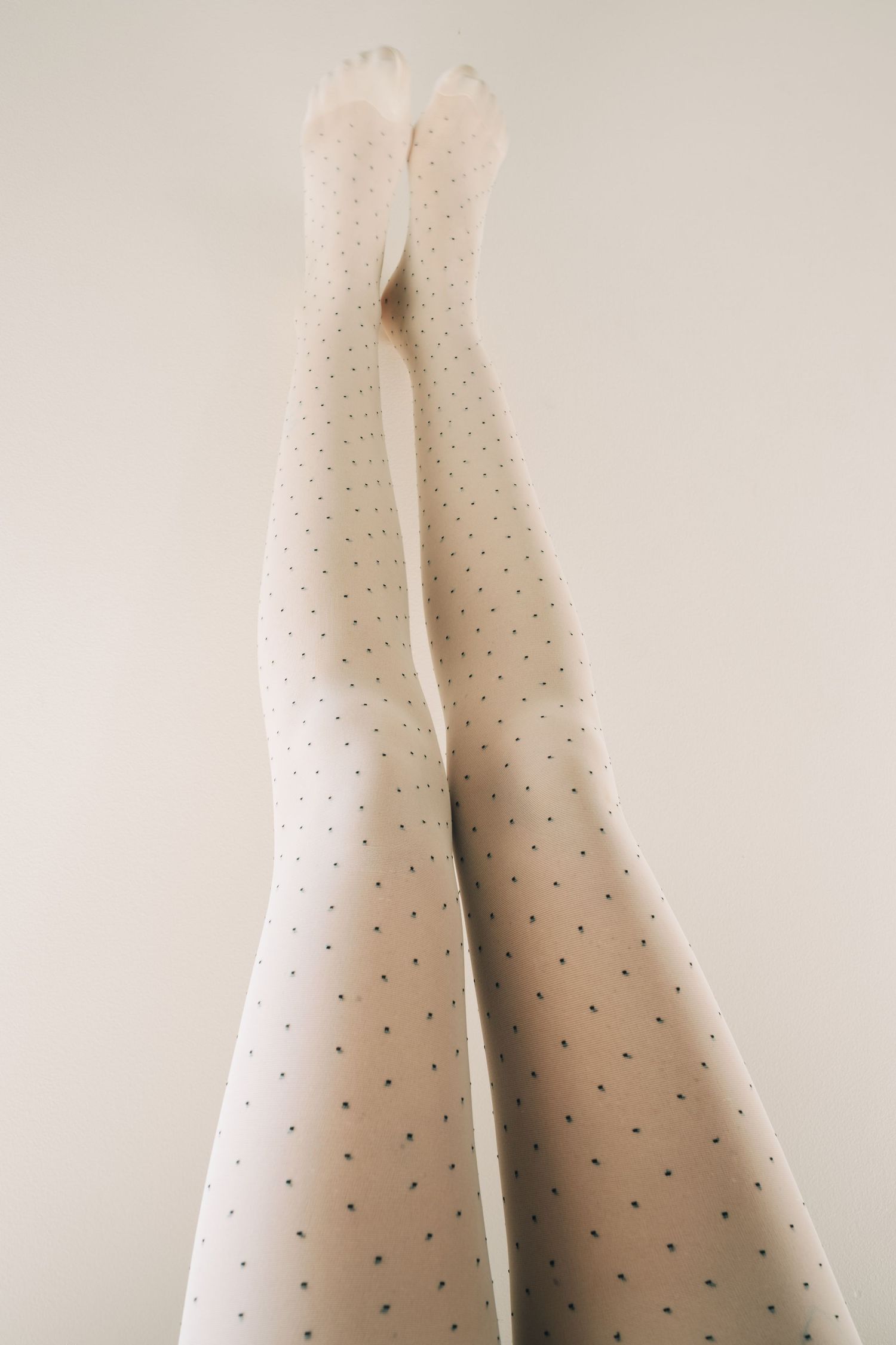 White polka dot stockings against light background in minimalist style.