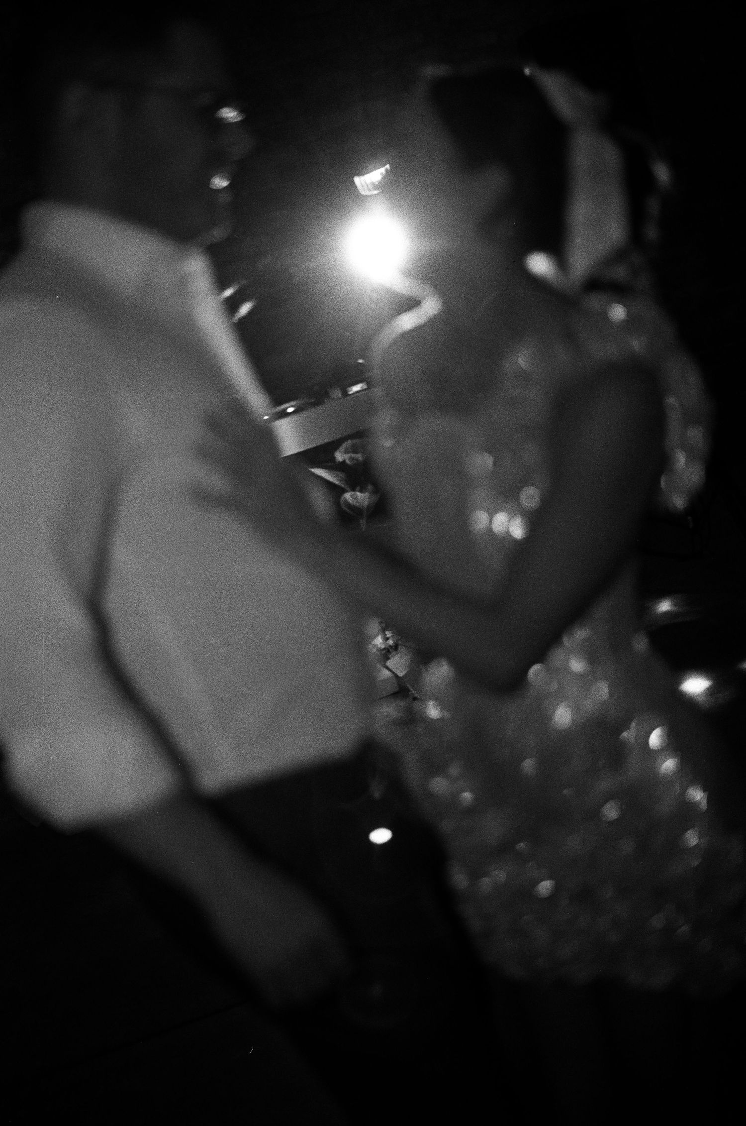 Couple shares first dance in black and white photo with soft bokeh lighting.