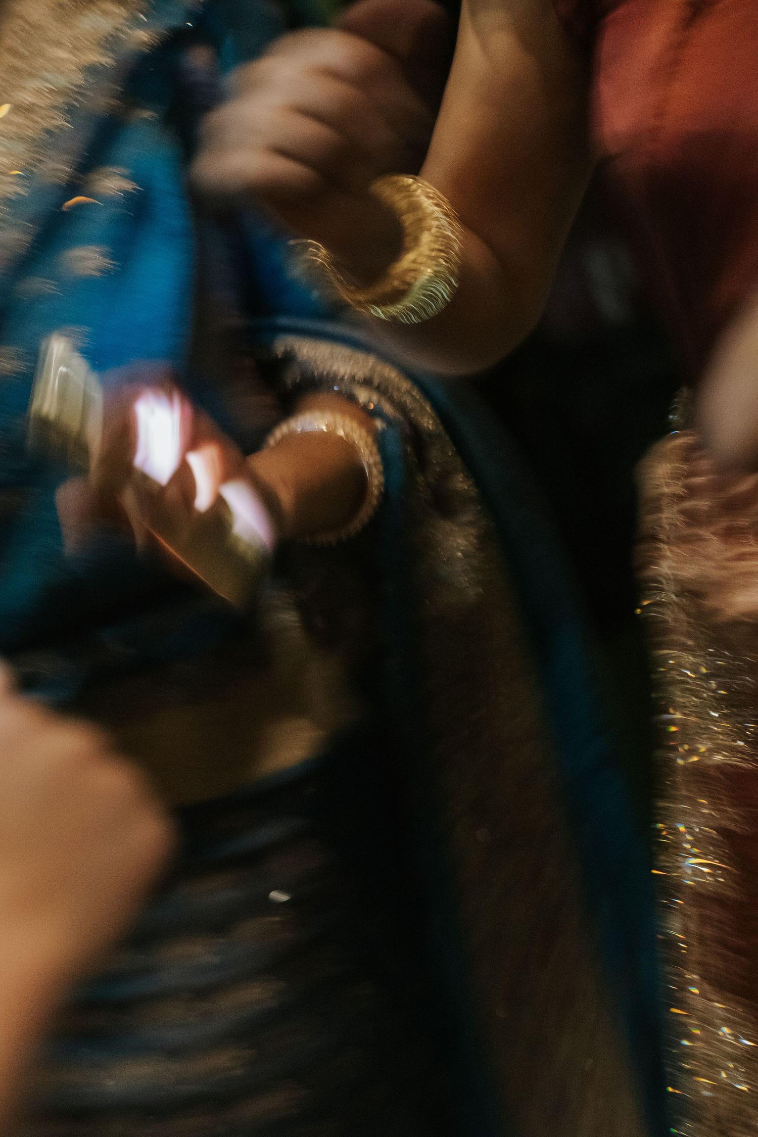 Blurred close-up of hands adorned with gold bangles in colorful traditional Indian attire.