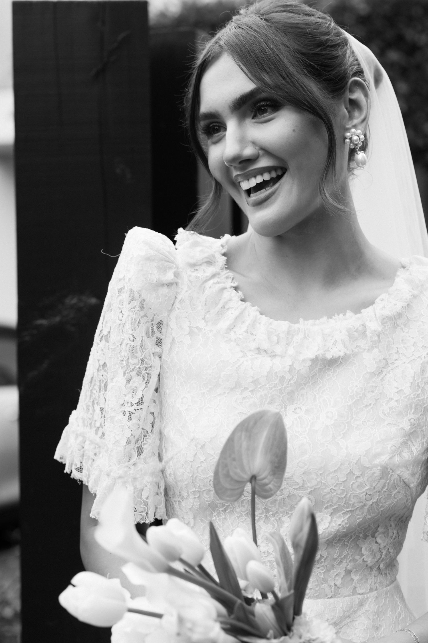Black and white portraits of a bride in delicate lace wedding dress showing joyful expressions.