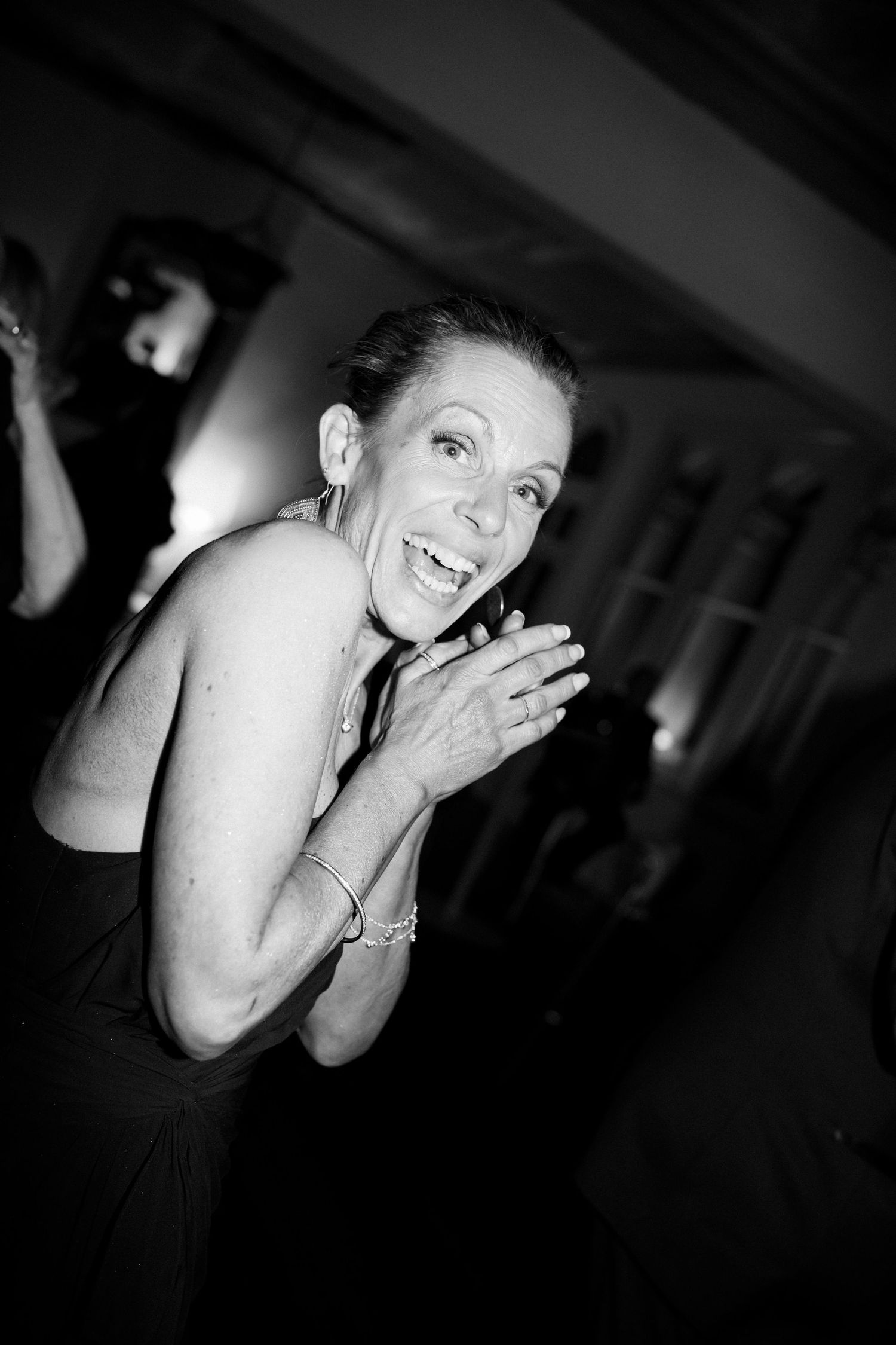 A dramatic black and white portrait of a guest laughing on the dancefloor at Sophia Prahran