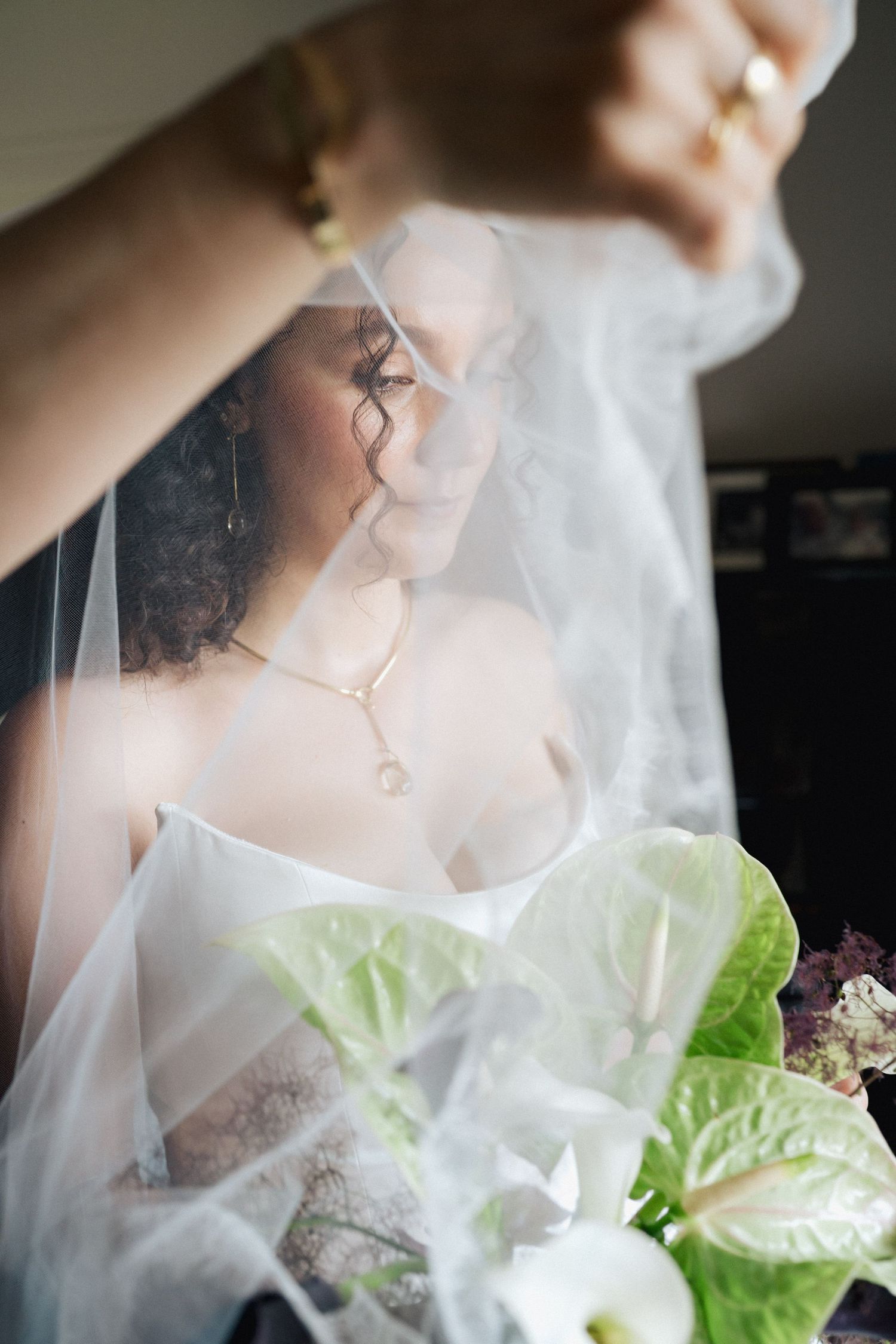 Close-up of bridal details showing delicate veil and white anthurium bouquet.